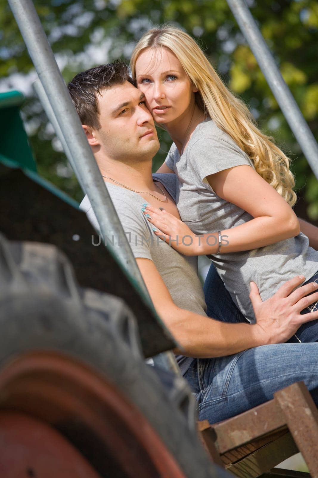 young couple sitting on tractor in countryside