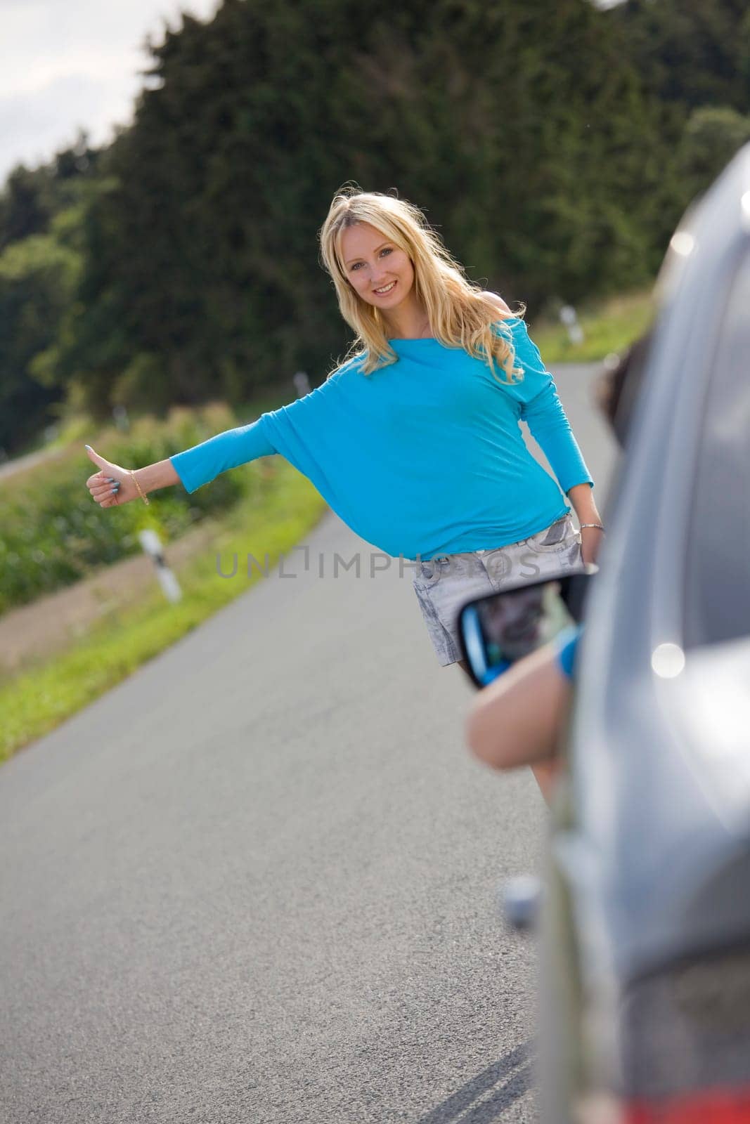 young blonde woman stopping car in countryside