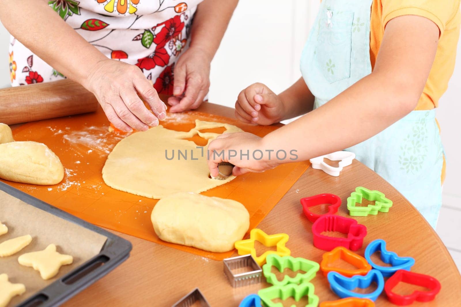 Detail of hands cutting pastry - child and adult