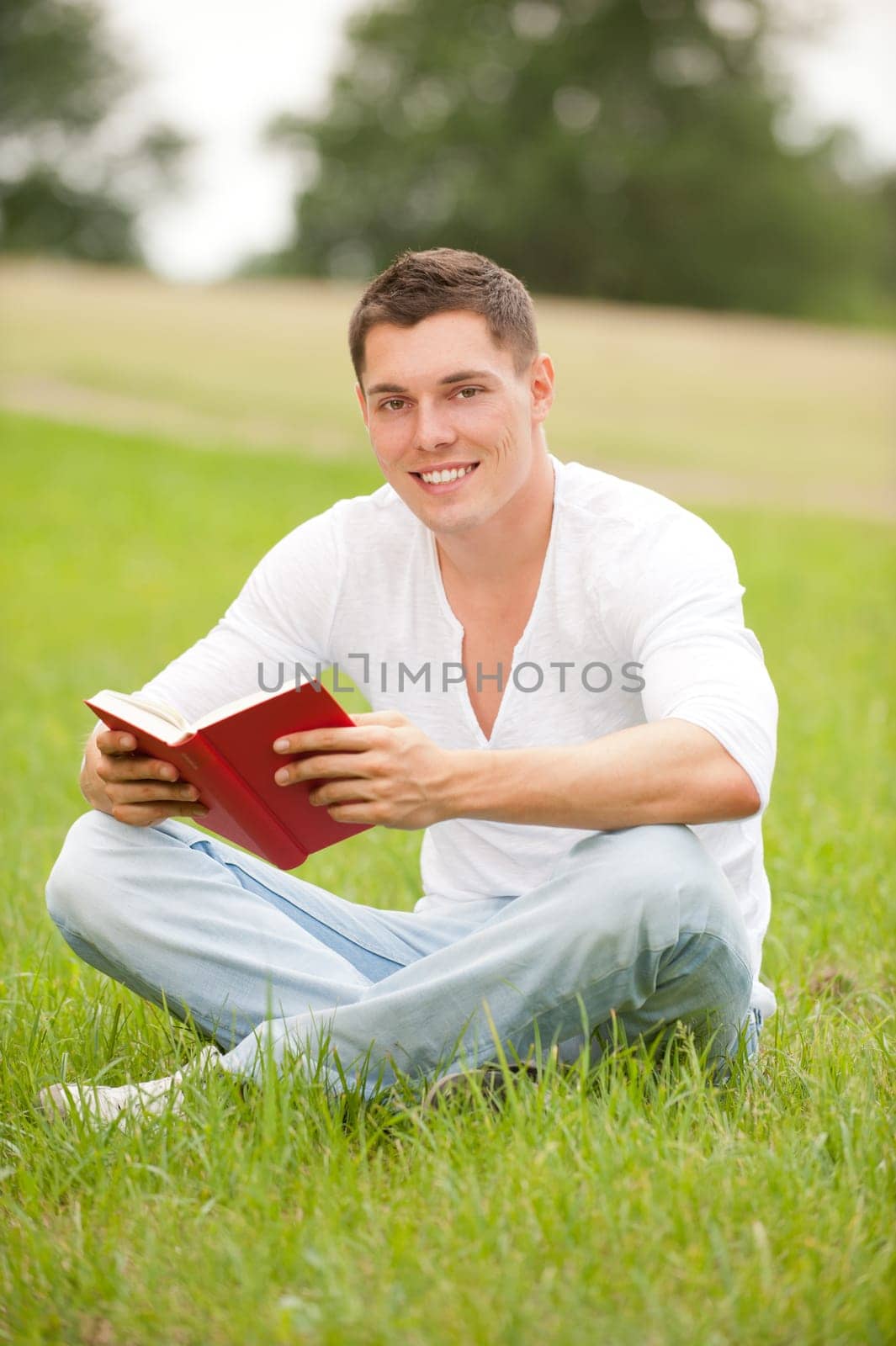 Young man with a book in a meadow