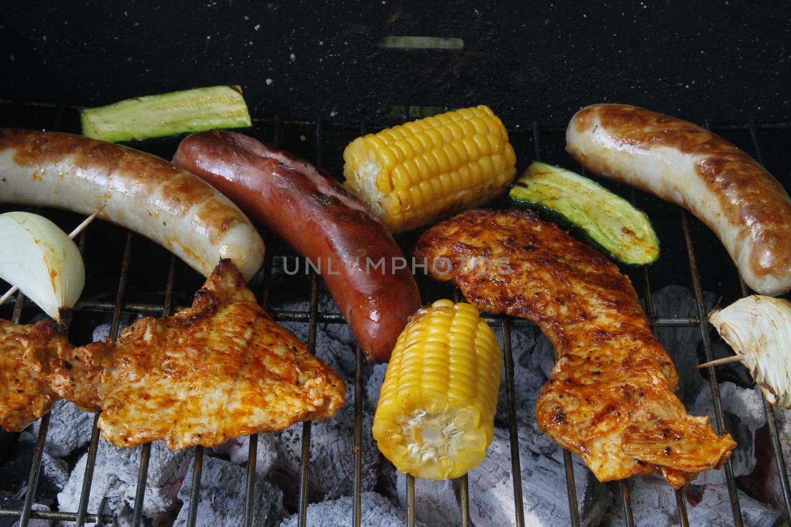 colorful grilled food on a charcoal grill with meat,sausages,corn,zucchini and onion