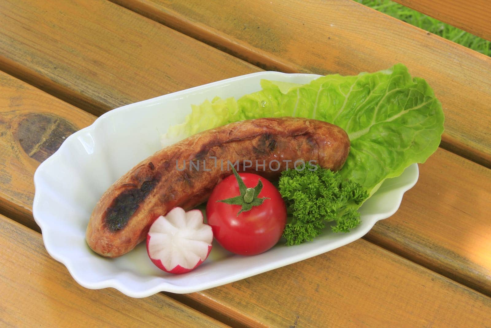 Grilled sausage,decoratively arranged with radishes,tomato,lettuce and parsley