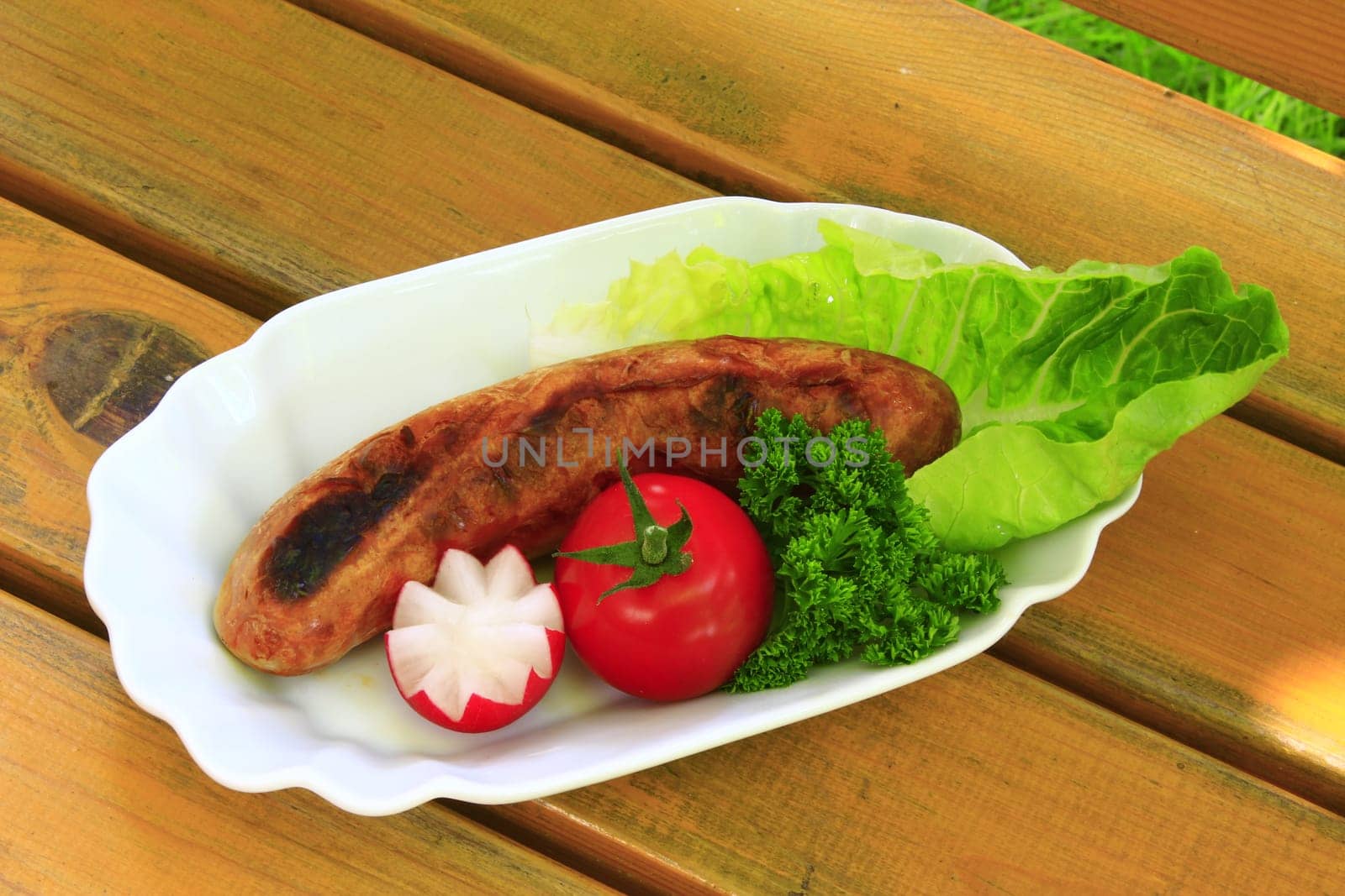 Grilled sausage,decoratively arranged with radishes,tomato,lettuce and parsley