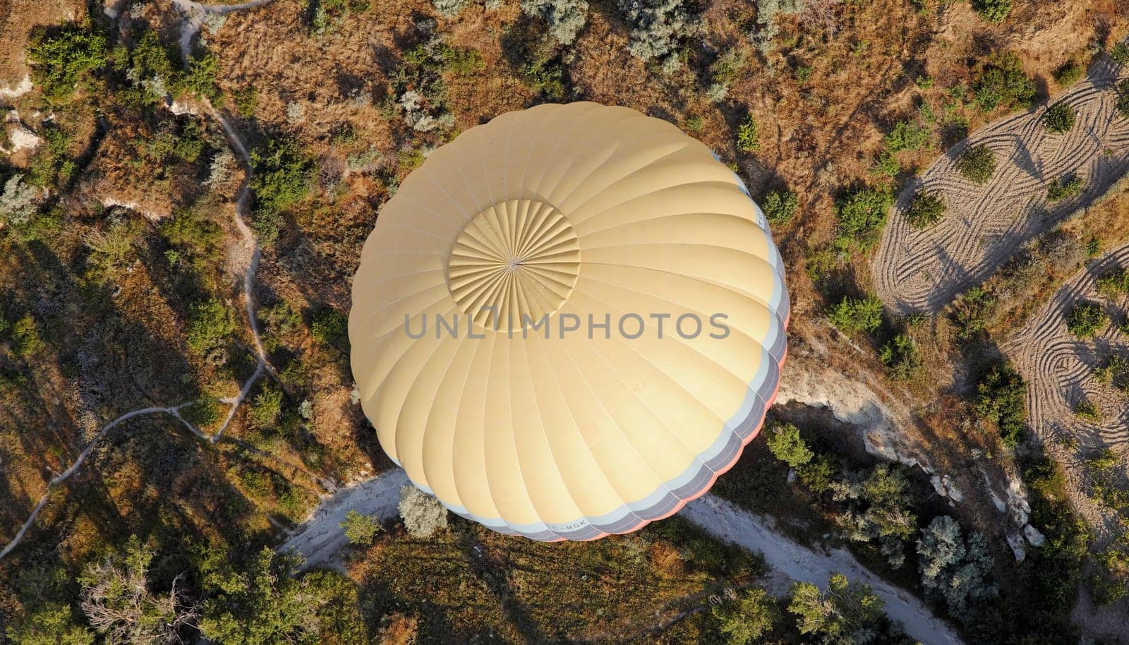 Multi Color banded yellow hot air balloon over the wilderness of Cappadocia, showing wilderness and farmlands, landscape, crop space, copy space