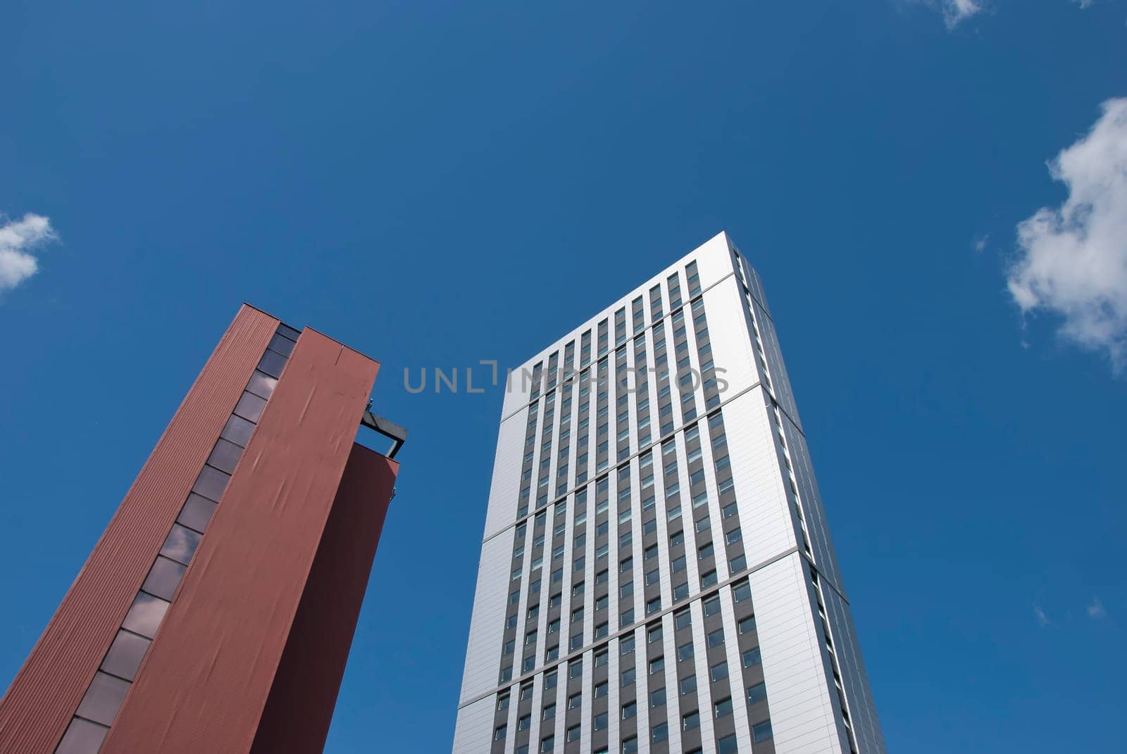 Two Red Brick and White Tower Blocks under a blue summer sky