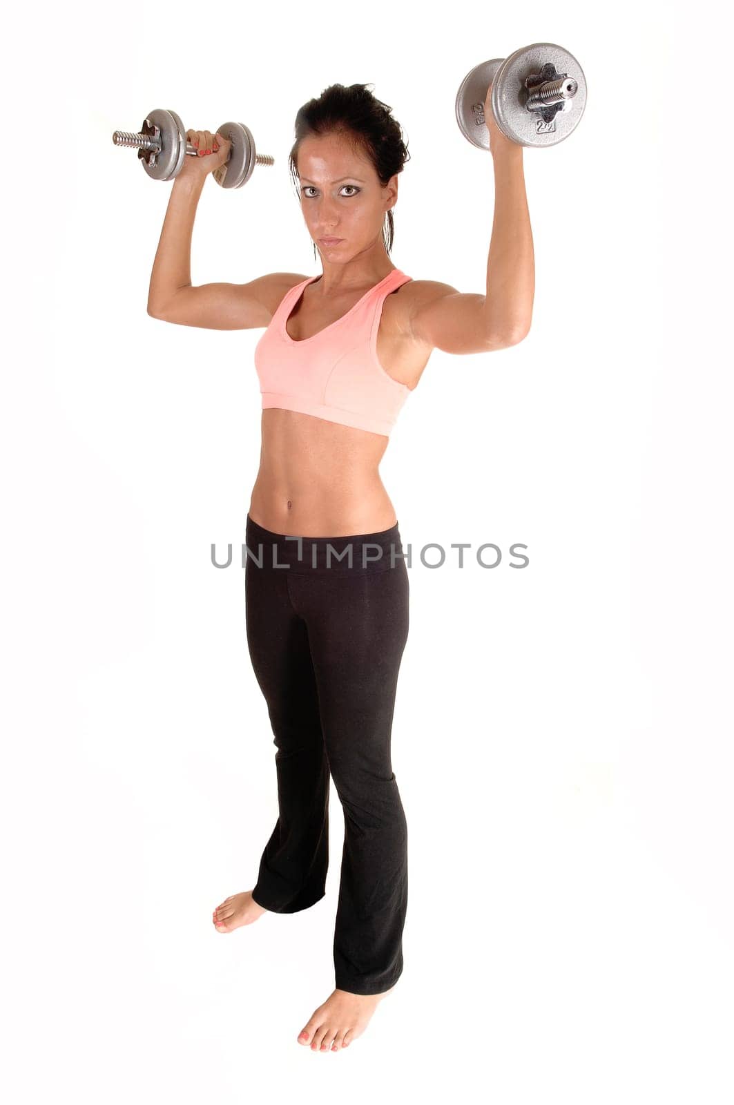 A pretty woman with dumbbells lifting, standing in the studio with bare feet, for white background.