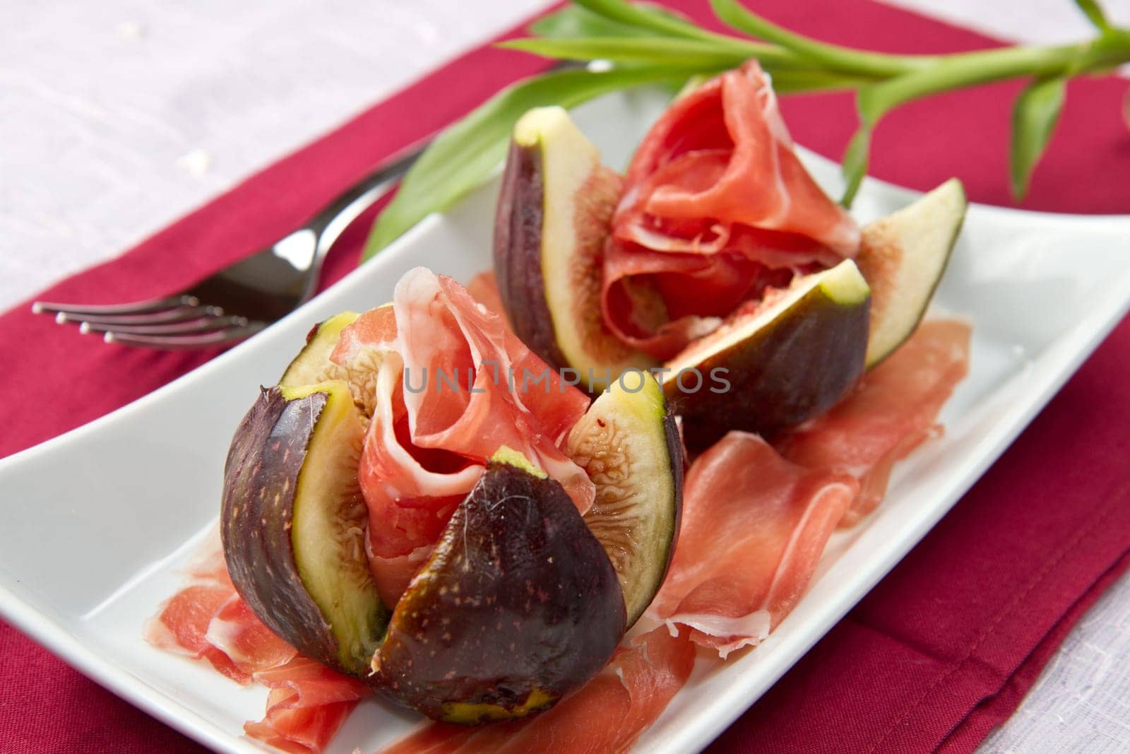 Fresh figs with ham on a white plate