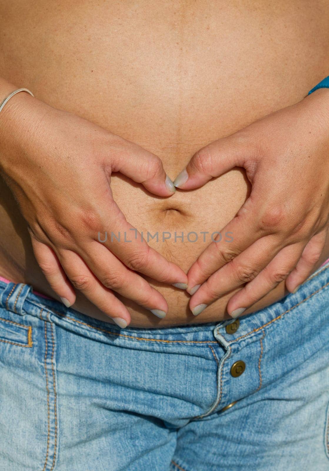 Pregnant woman making heart shape with hands over her stomach