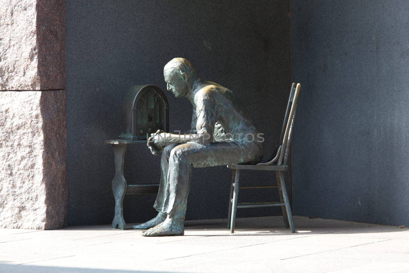 Distant telephoto shot of the statue in Roosevelt memorial of a poor hungry man listening to a fireside chat on the radio in Washington DC