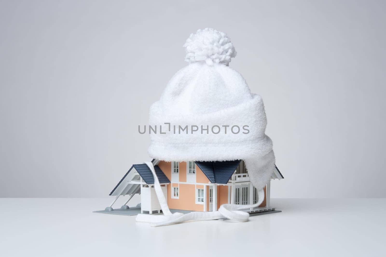 Baby cap isolate model of the house against heat leak - house insulation concept. Gray background.