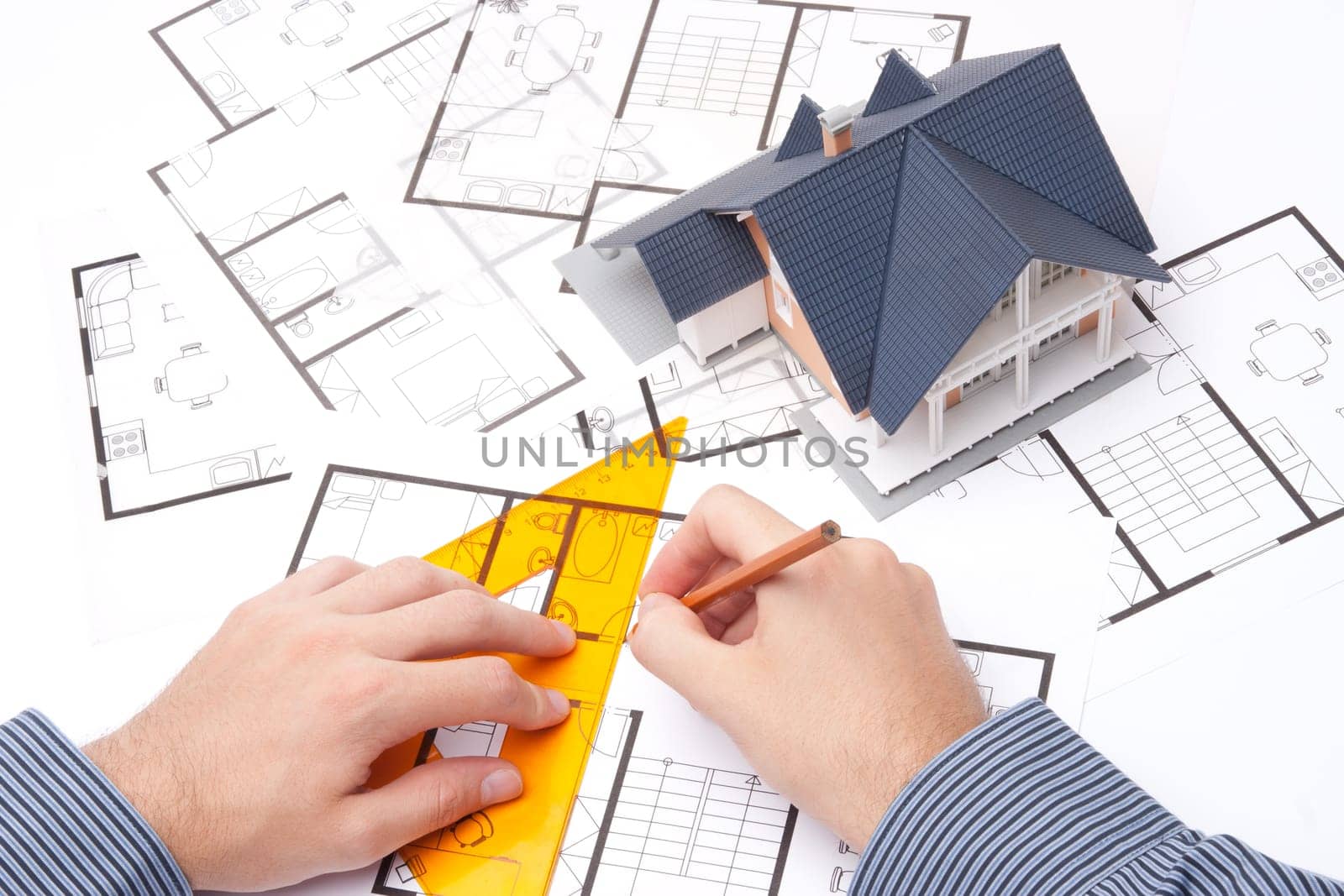 Architect working with blueprints and model of the family house