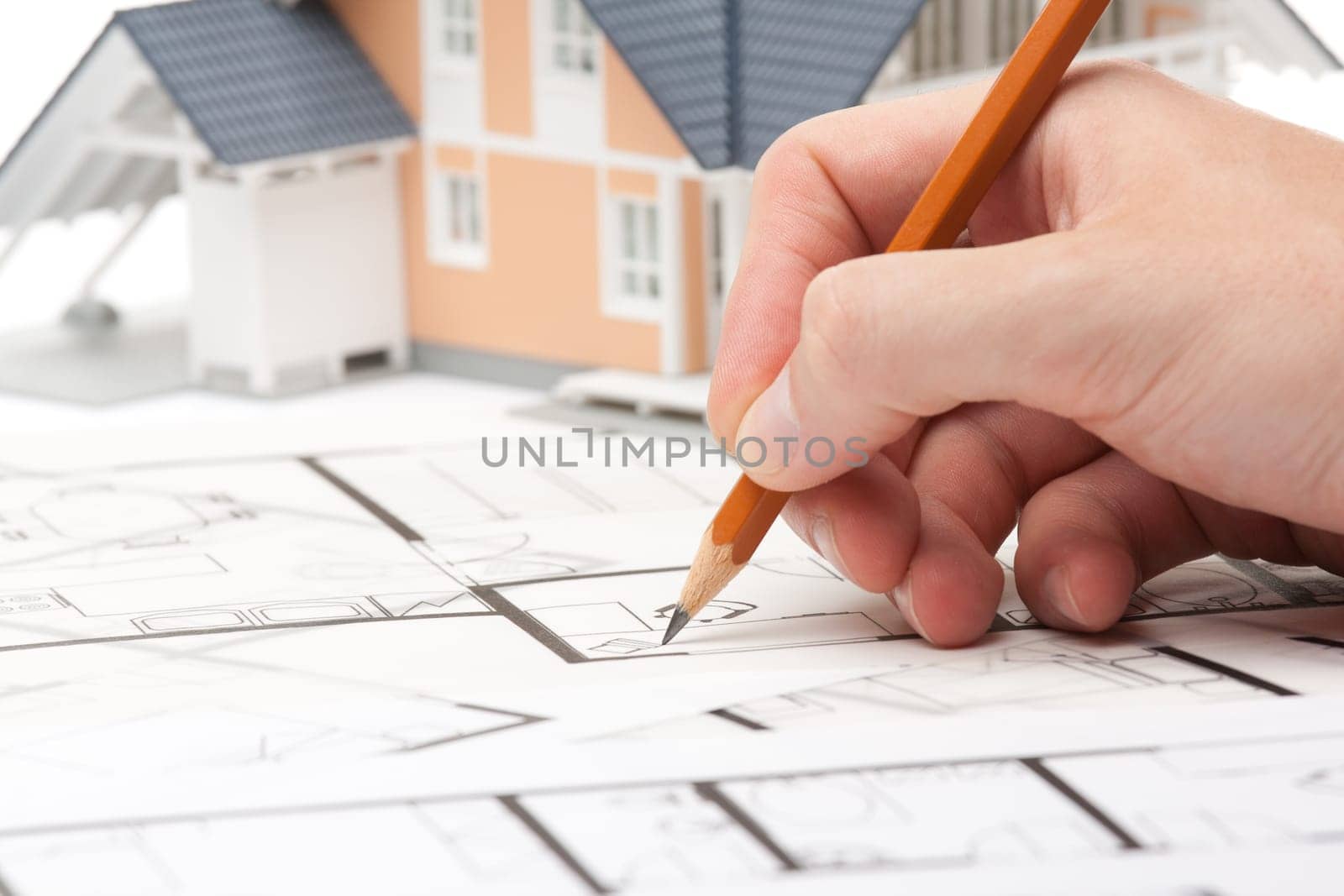 Architect working with blueprints and model of the family house