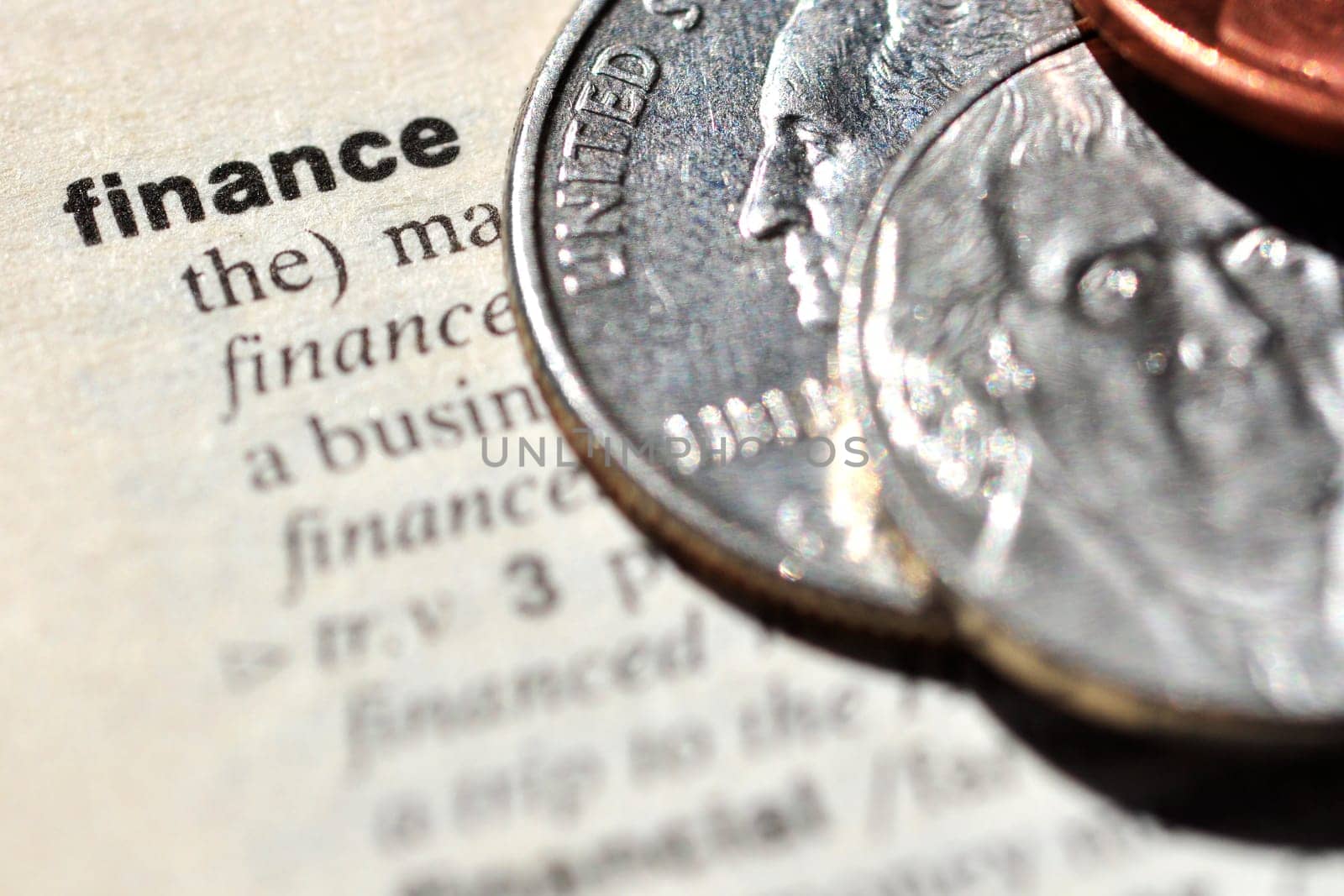 The word "finance"", written on a dictionary, next to some United States of America coins"