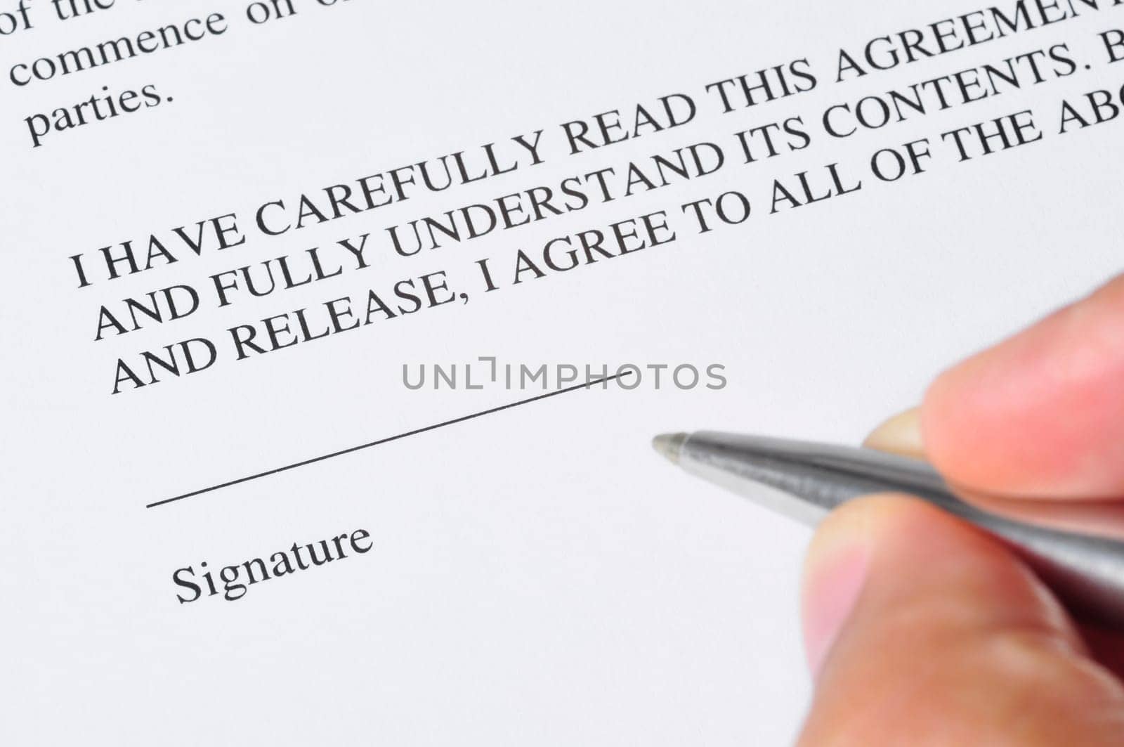 A hand, holding a pen, is ready to sign a document