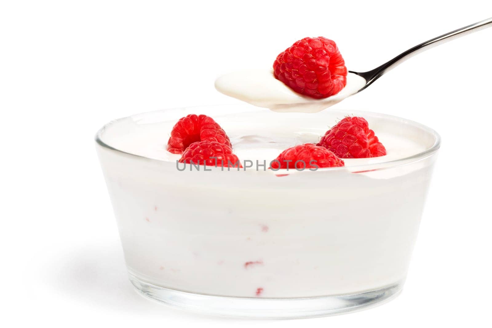 Raspberry on a spoon with yogurt over a dessert on a white background