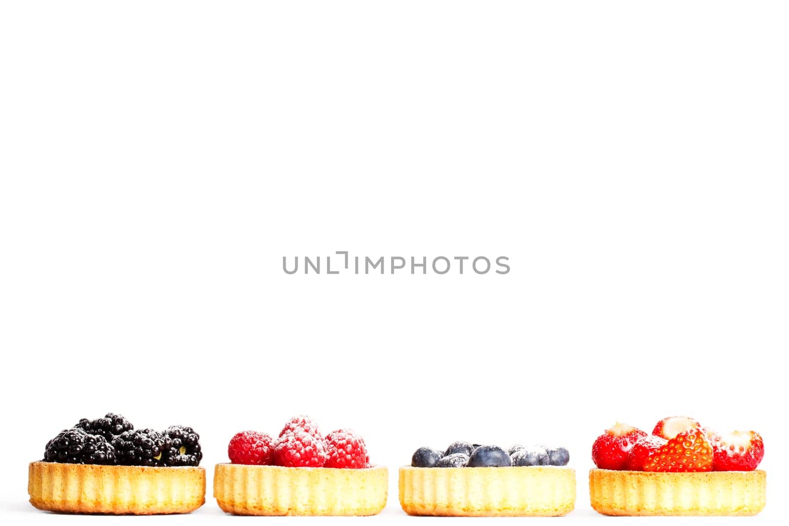Set of sugared wild berries in tartlet cake on white background