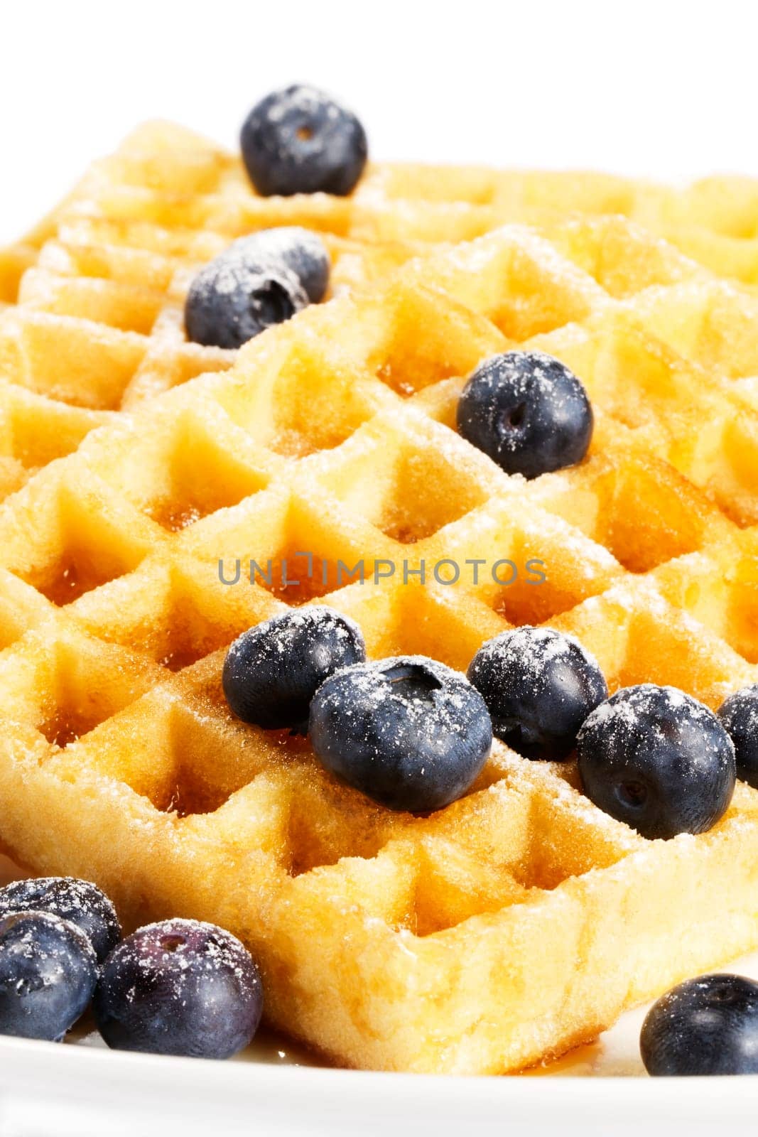 Waffles with sugared blueberries and syrup on white background