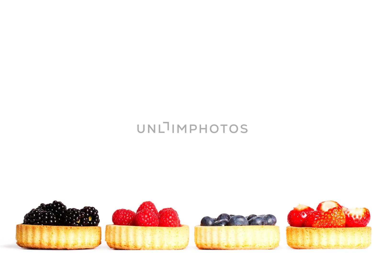 Set of tartlet cakes with wild berries on white background