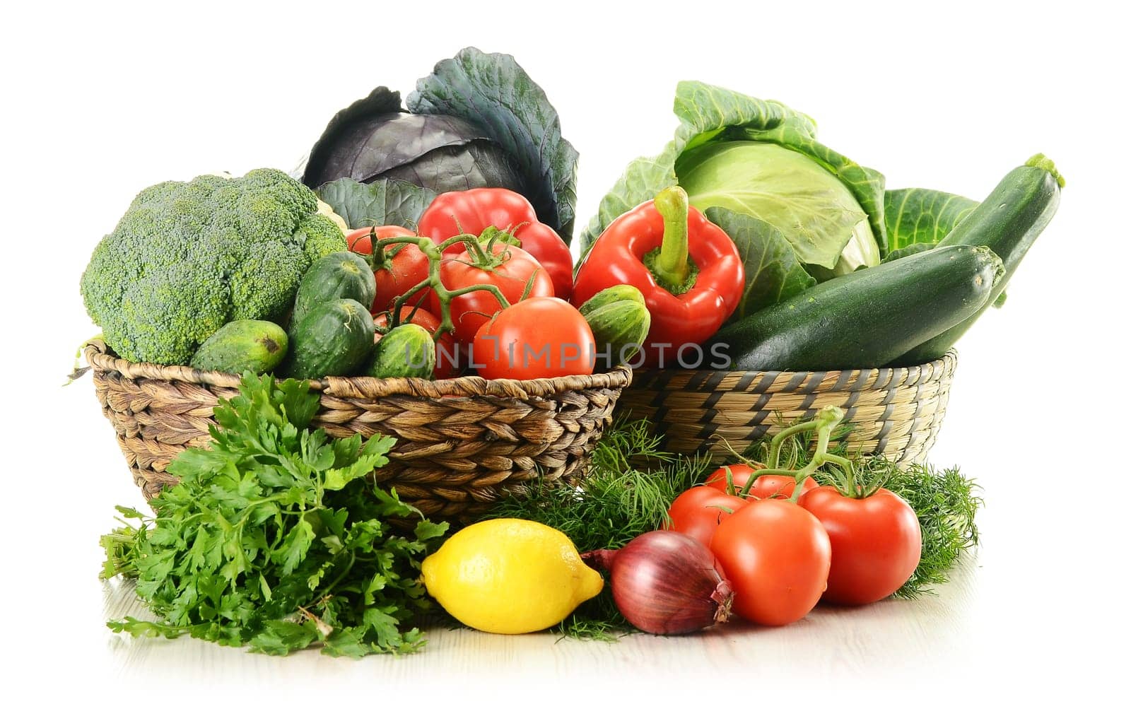 Composition with raw vegetables and wicker baskets isolated on white
