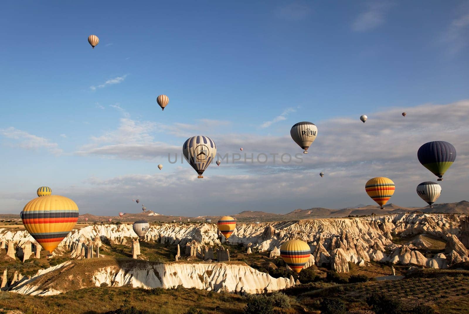 Cappadocia, Turkey: June 2011 - skies over Cappodiocia Kapadokya filled with colorful hot air ballons, blue sky, wispy clouds, mountain landscape and rough terrain