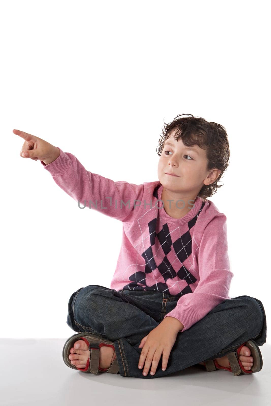 Beautiful child pointing with his finger sitting on a over white background