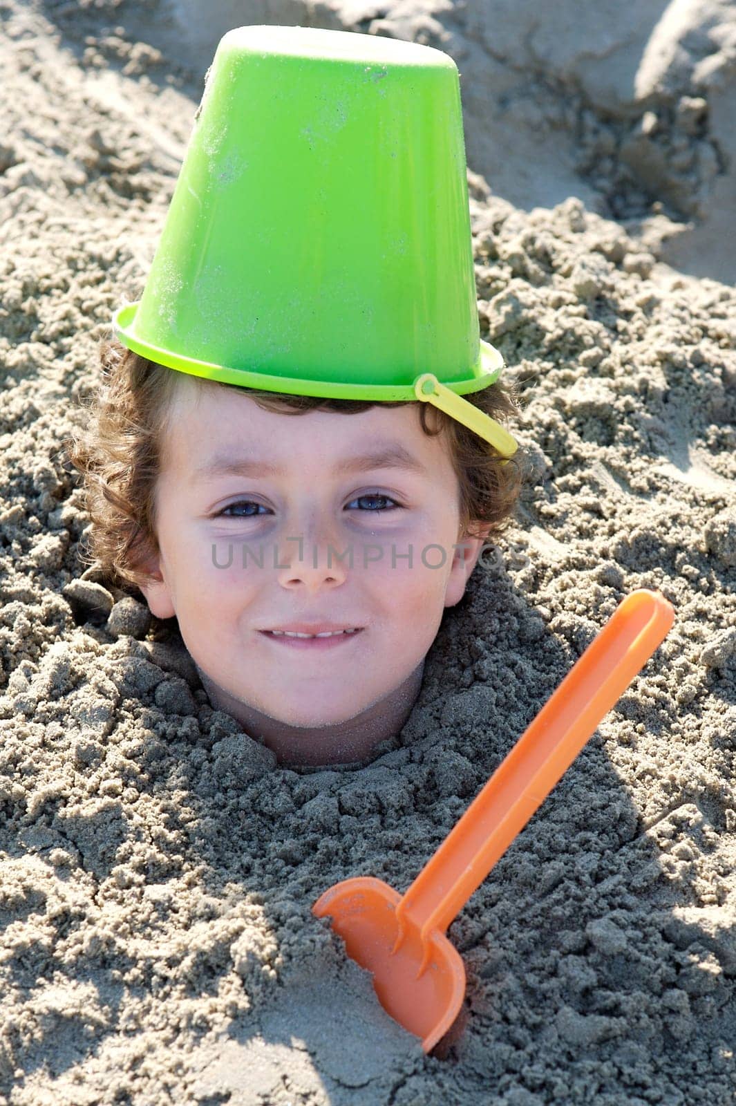 Small child buried in the sand of the beach