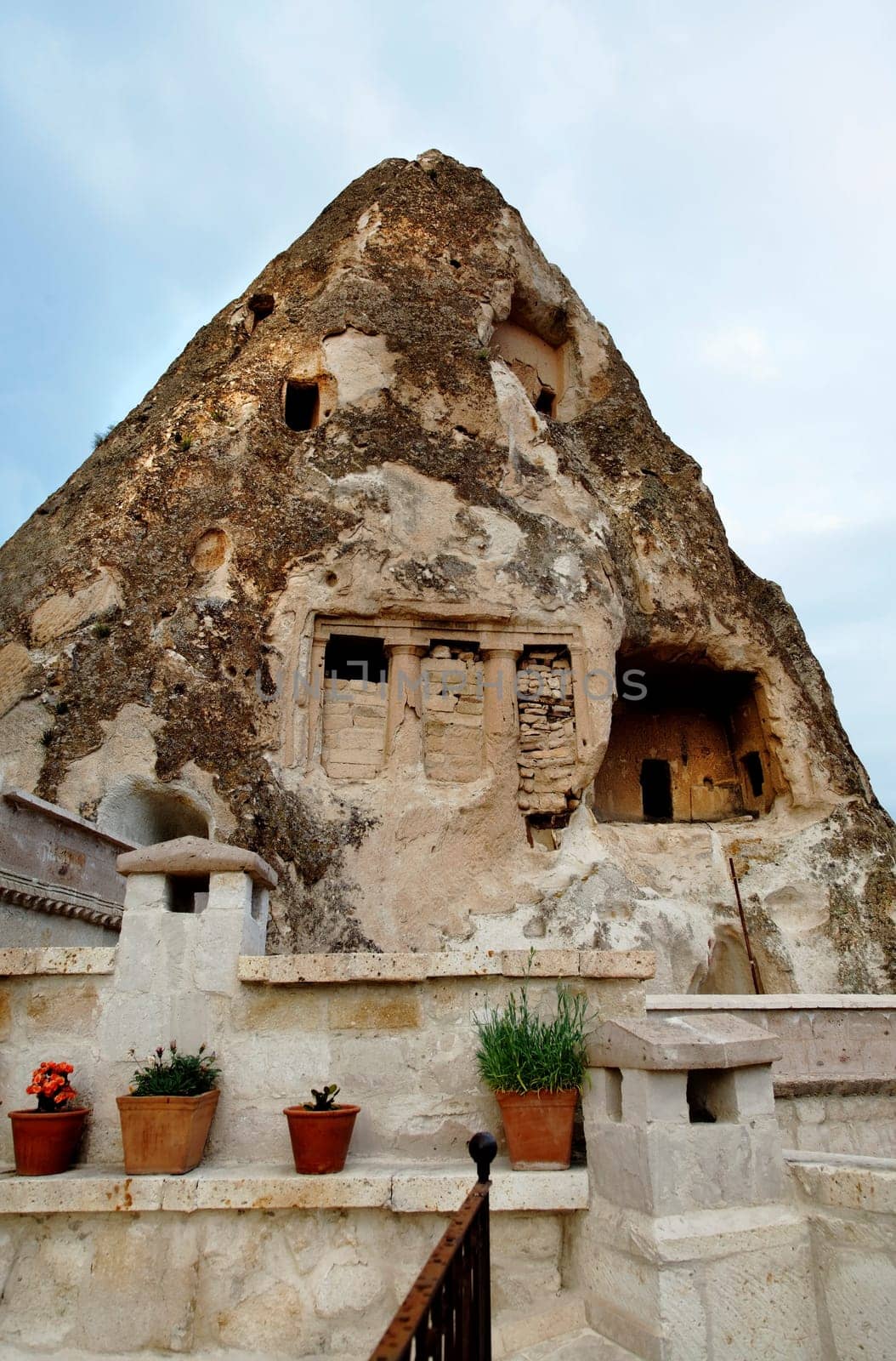 Close up of Limestone cave and veranda of a man made habitat dating to Roman era, blue sky, clouds, portrait, crop space, copy space