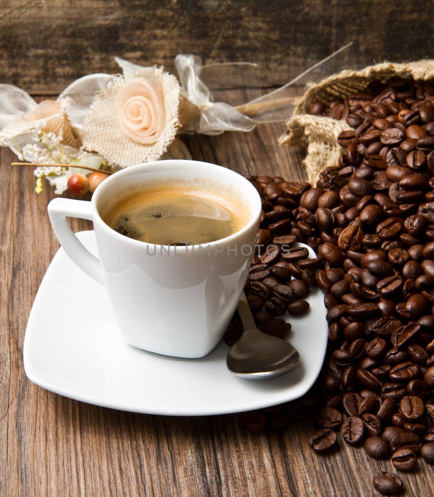 Coffee cup with burlap sack of roasted beans on rustic table