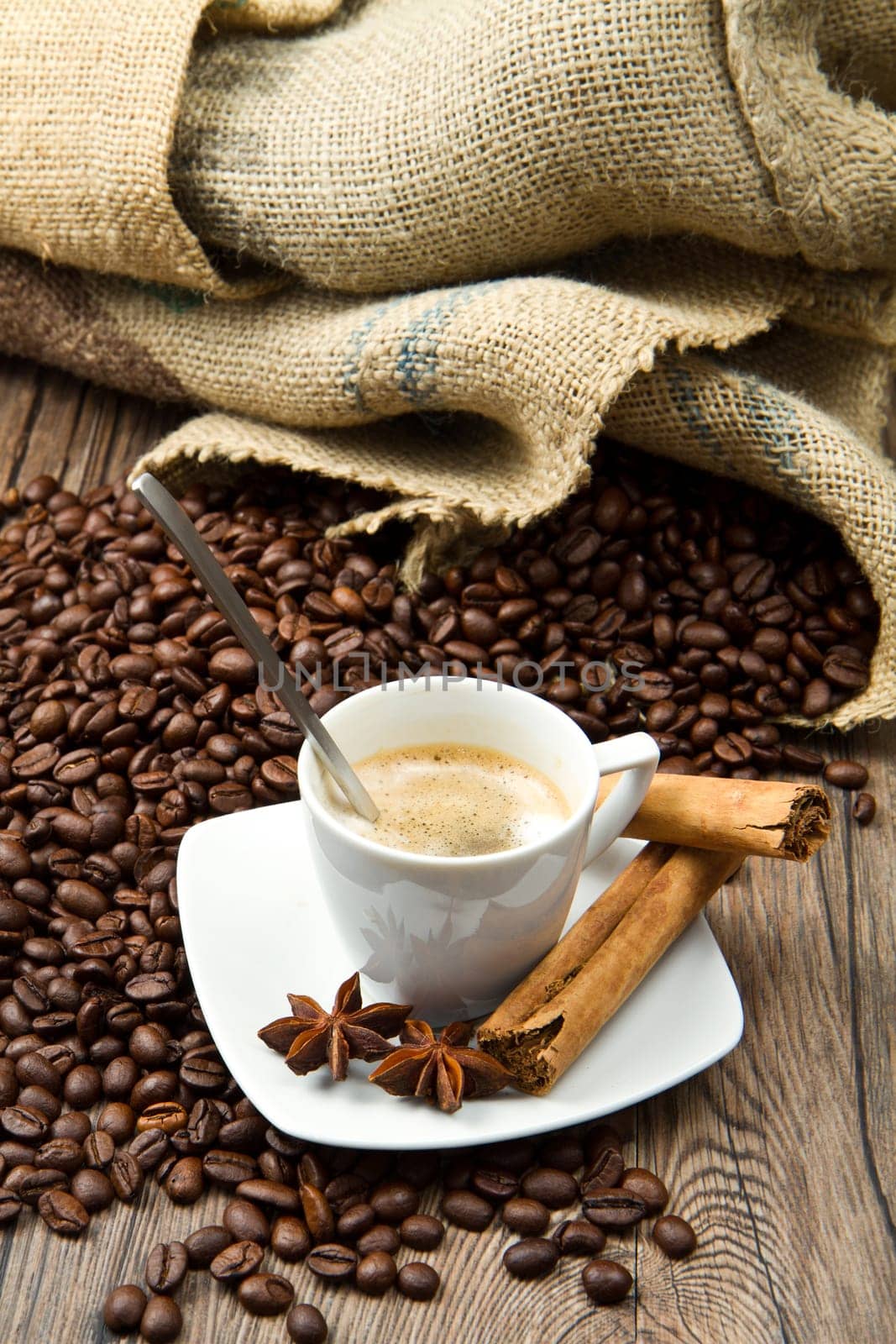 Coffee cup with burlap sack of roasted beans on rustic table