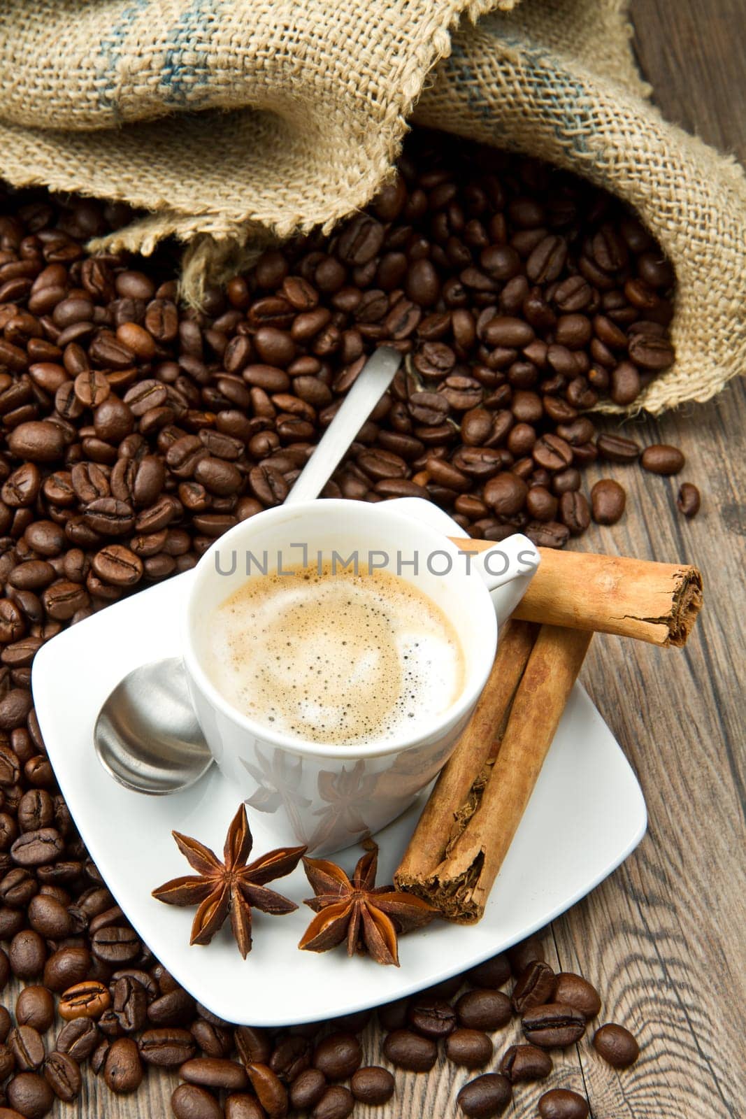 Coffee cup with burlap sack of roasted beans on rustic table