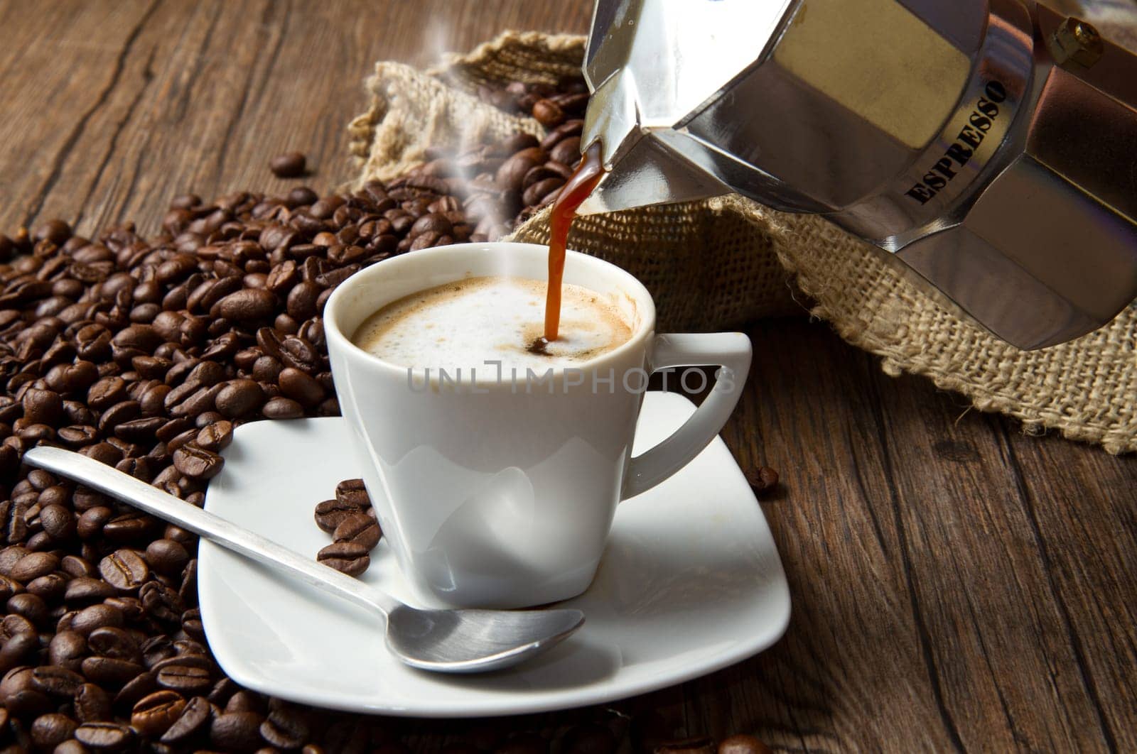 Coffee cup with burlap sack of roasted beans on rustic table