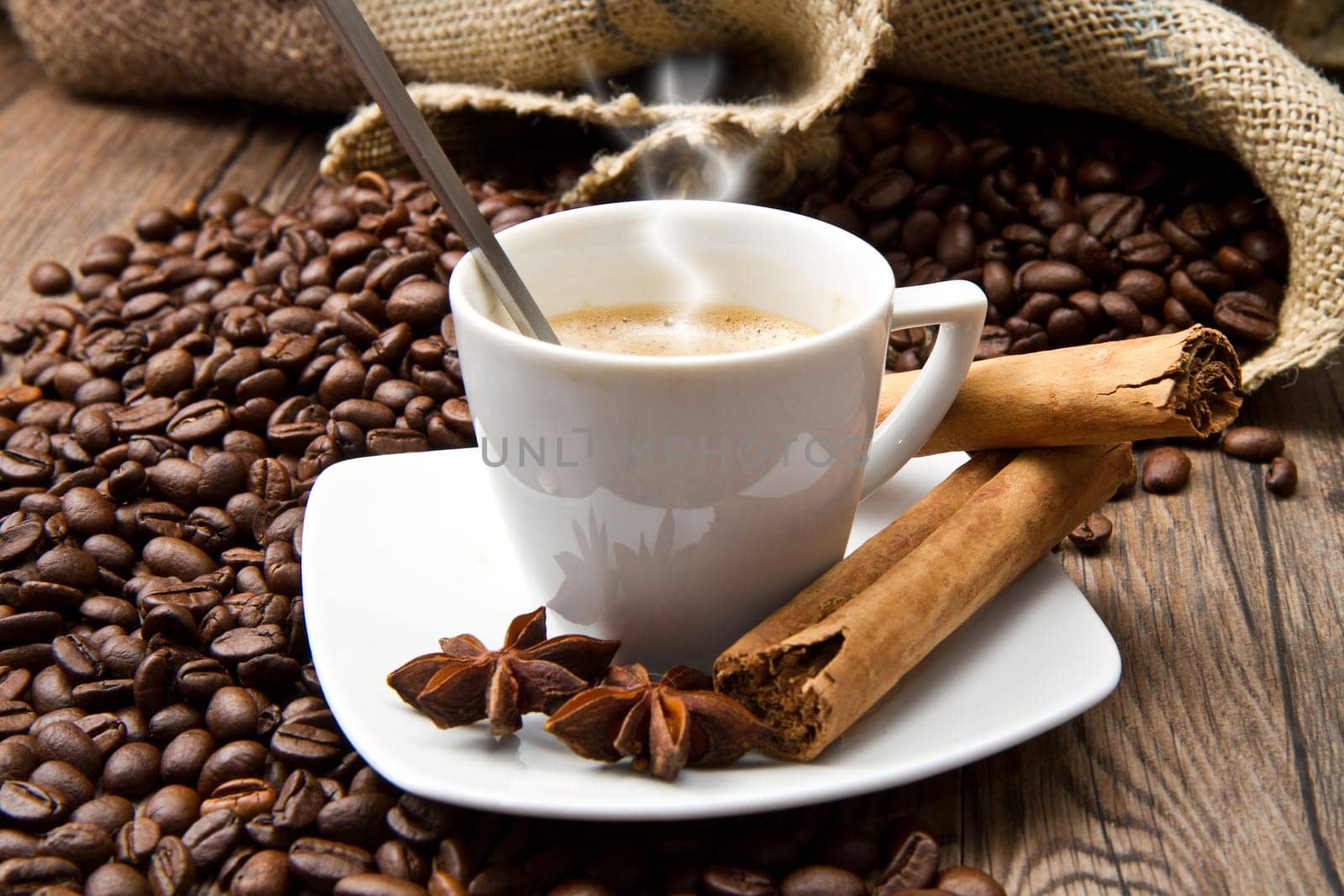 Coffee cup with burlap sack of roasted beans on rustic table