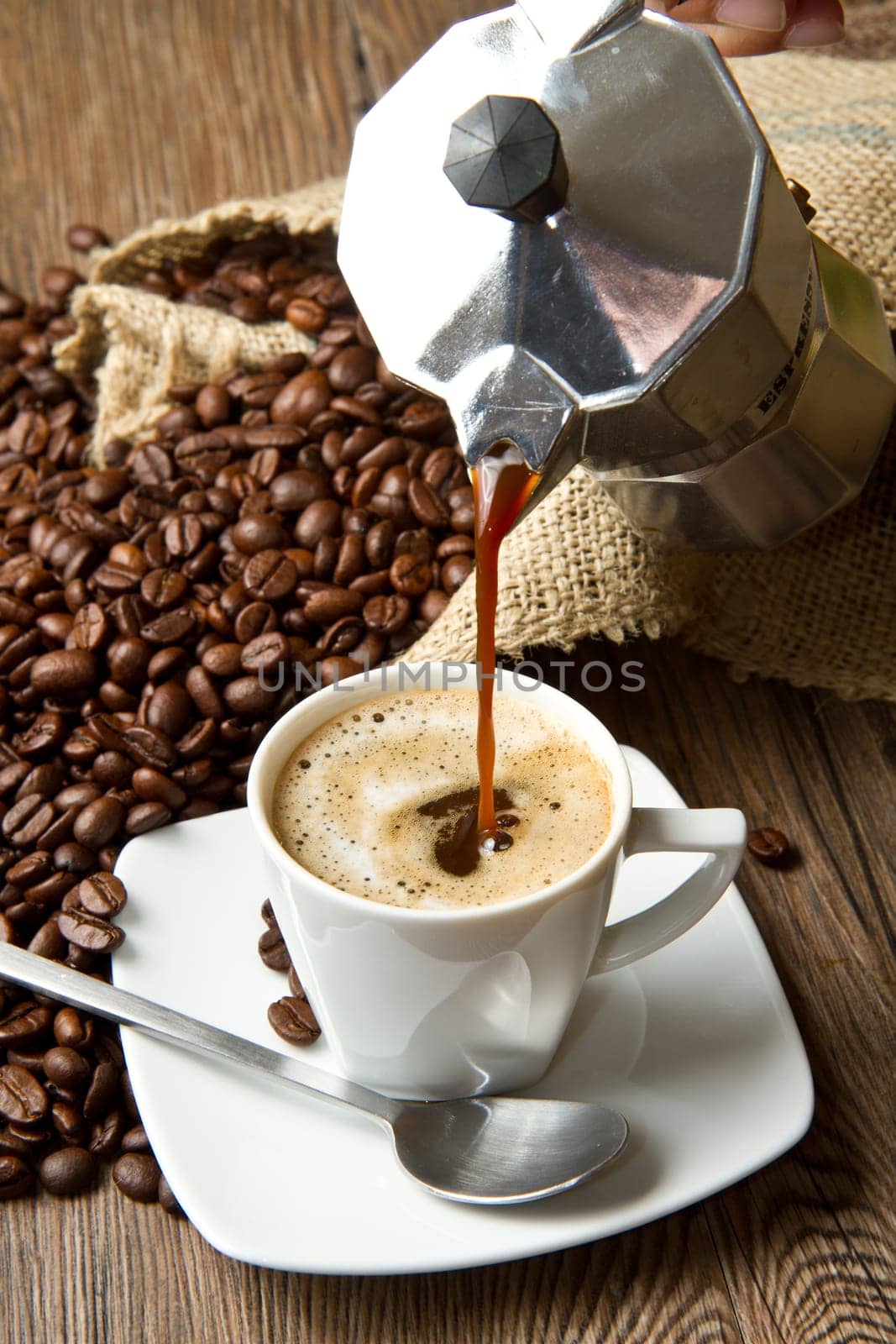 Coffee cup with burlap sack of roasted beans on rustic table