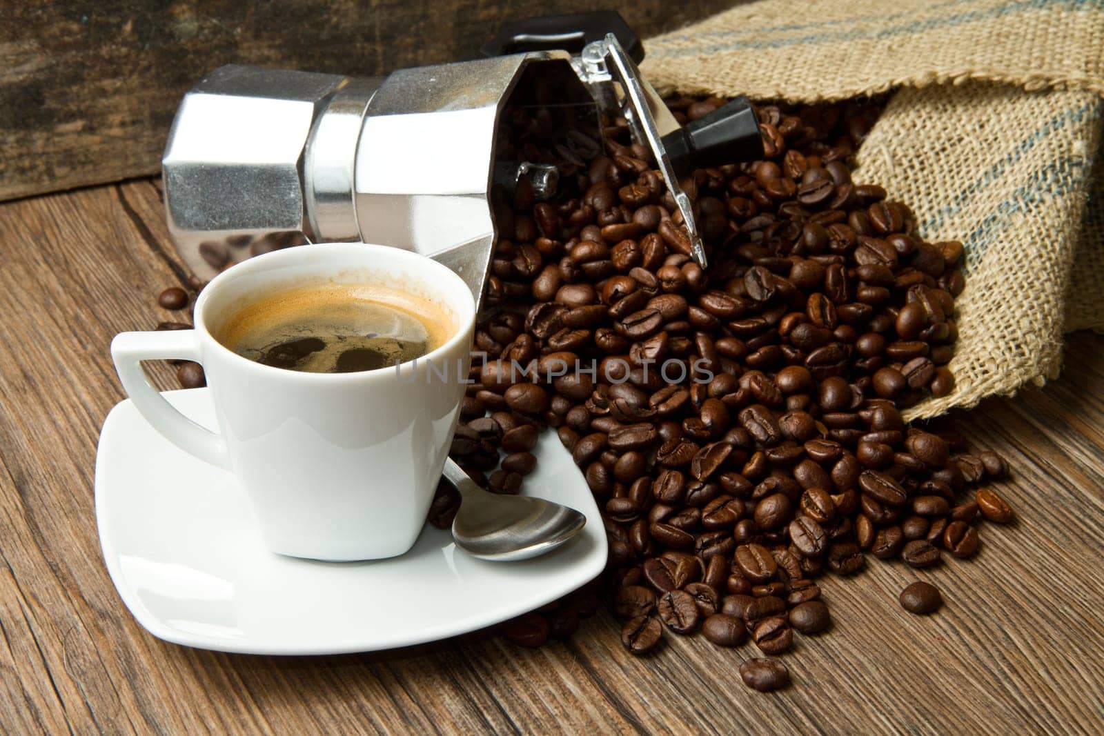 Coffee cup with burlap sack of roasted beans on rustic table
