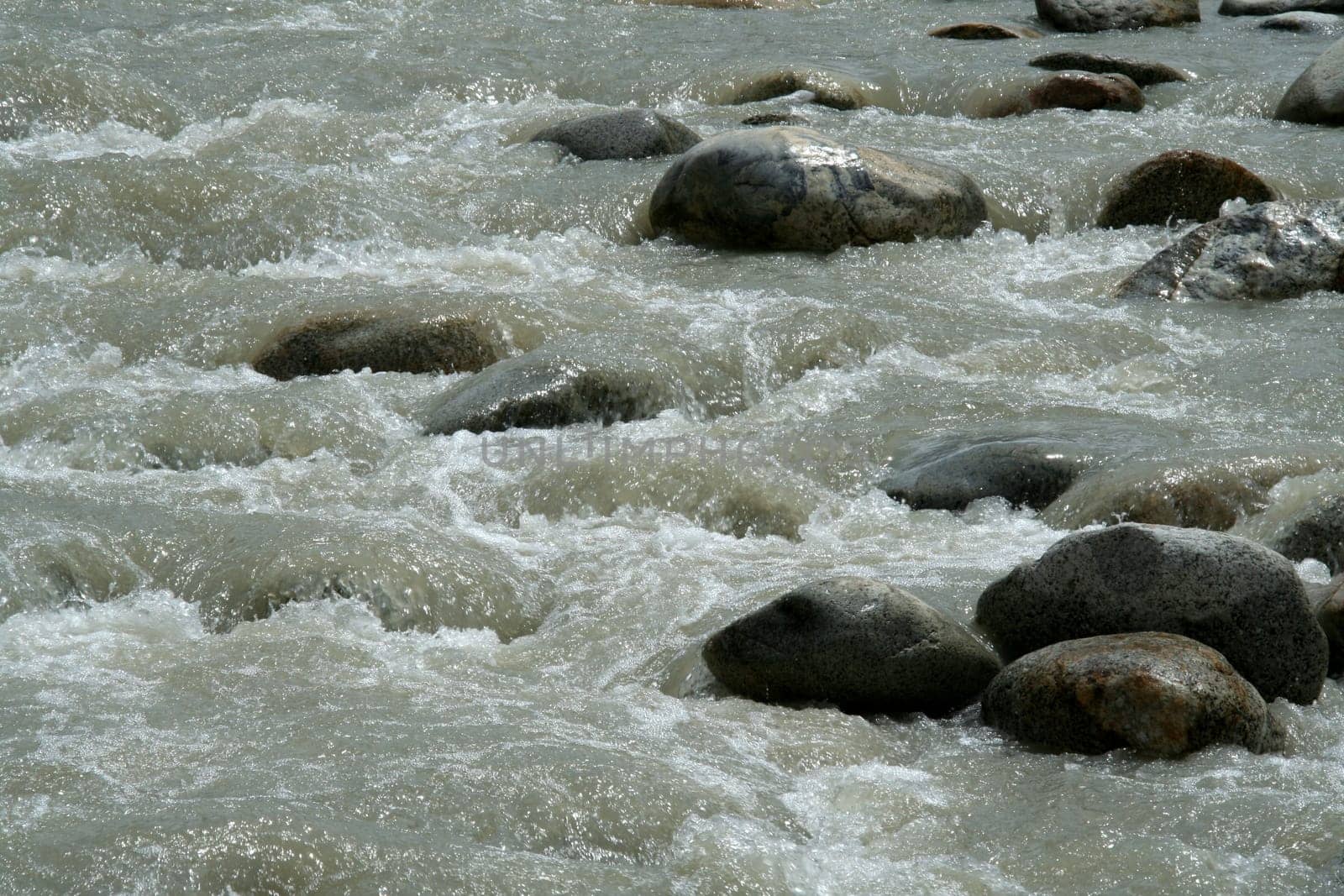 Dark and smooth rocks staying rigid amidst turbulent flow of water