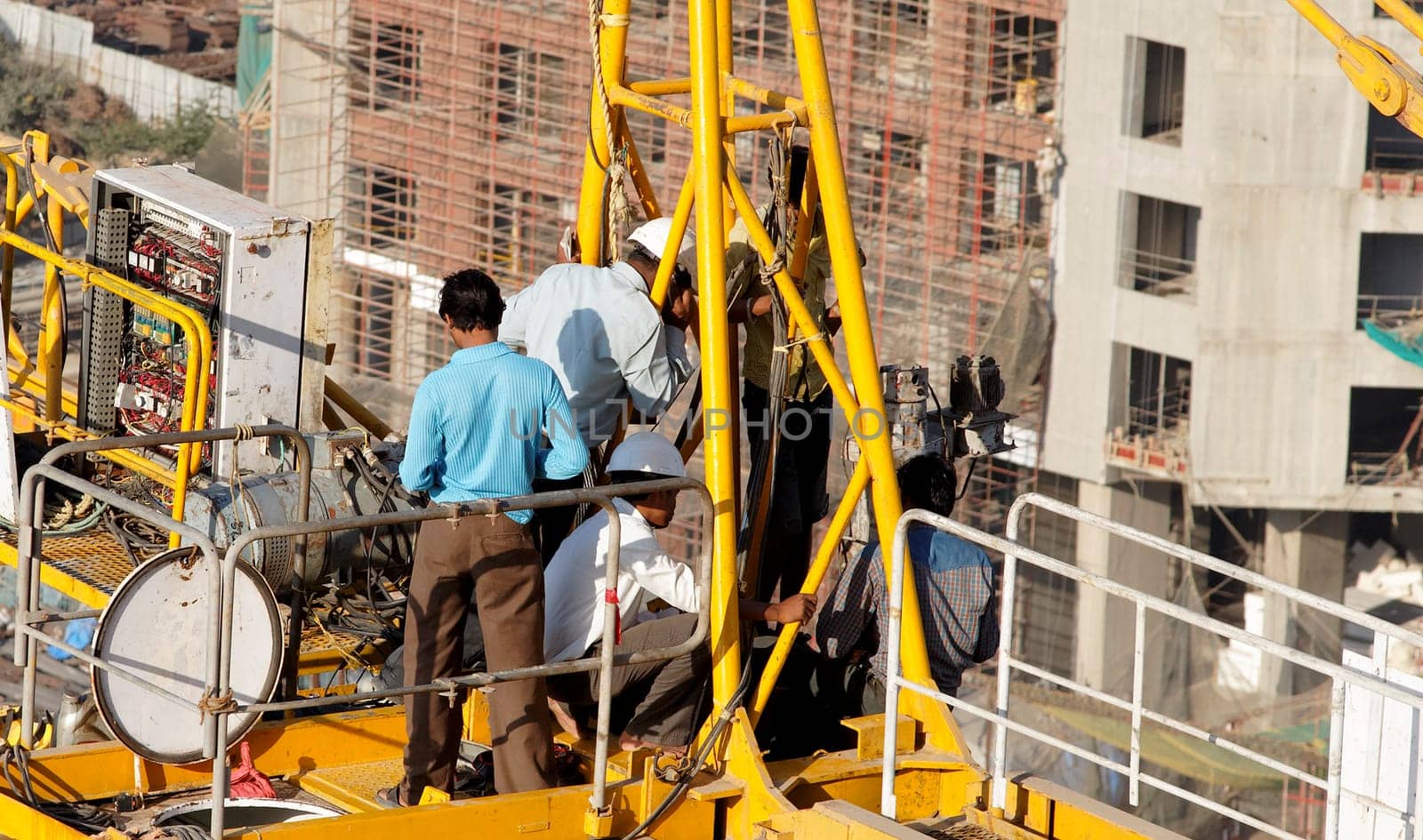 Mumbai, India - March, 2001:  men at work repairing the mechanics of a crane on a builders site