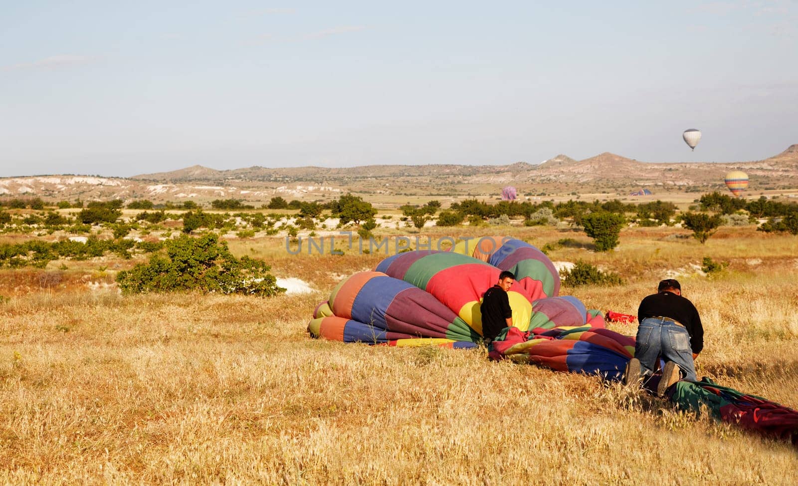 Cappadocia, Turkey - June, 2011: hot air balloons landing after flight and roadies packing them away for storage, horizontal, crop space, copy space and in the wilderness