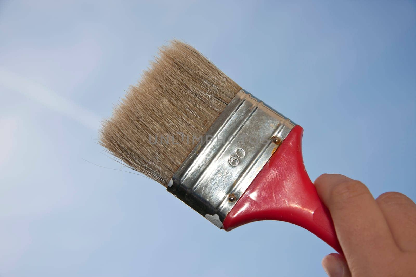 Hand holding flat brush in the sky