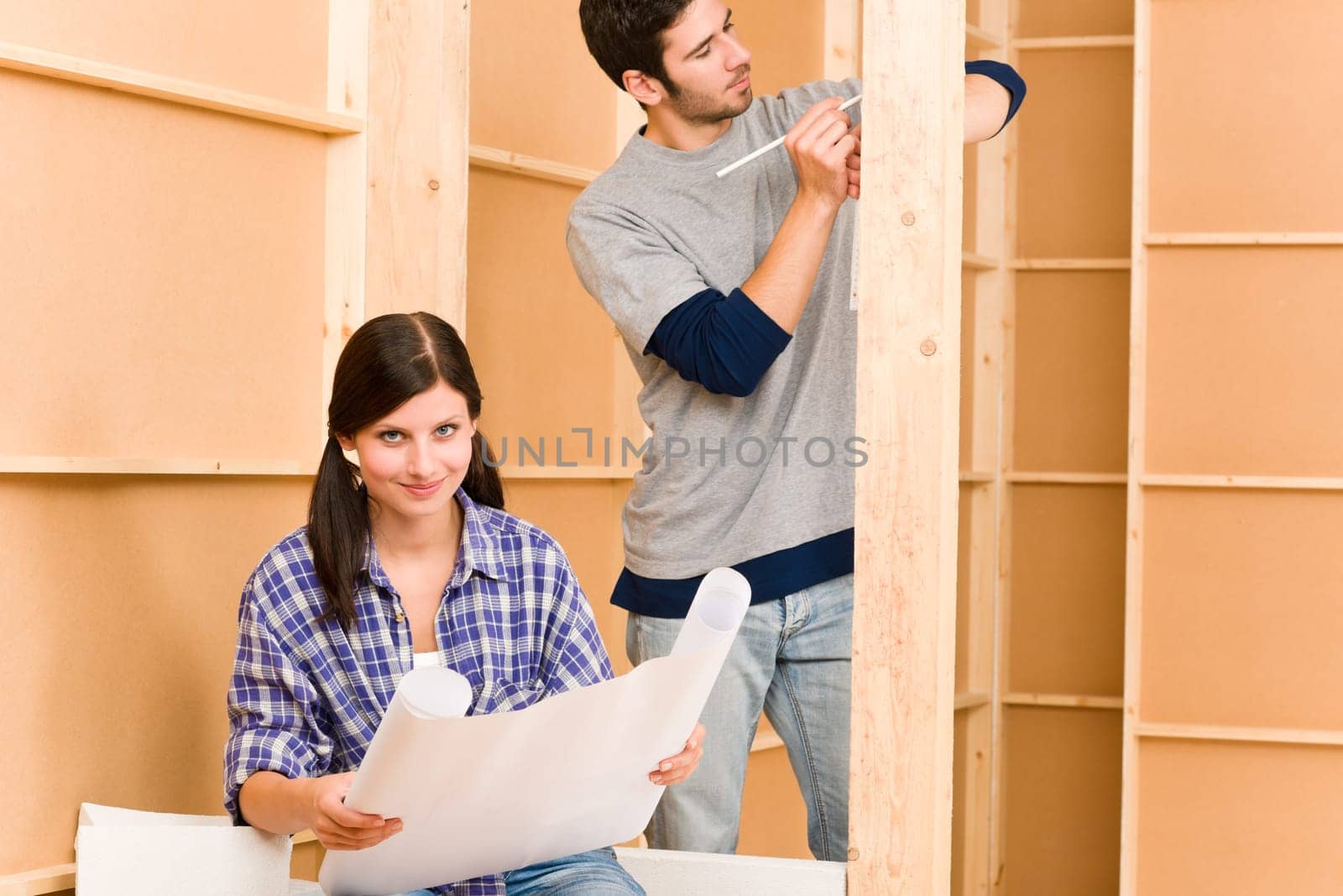 Home improvement happy young couple with architectural blueprints fixing house