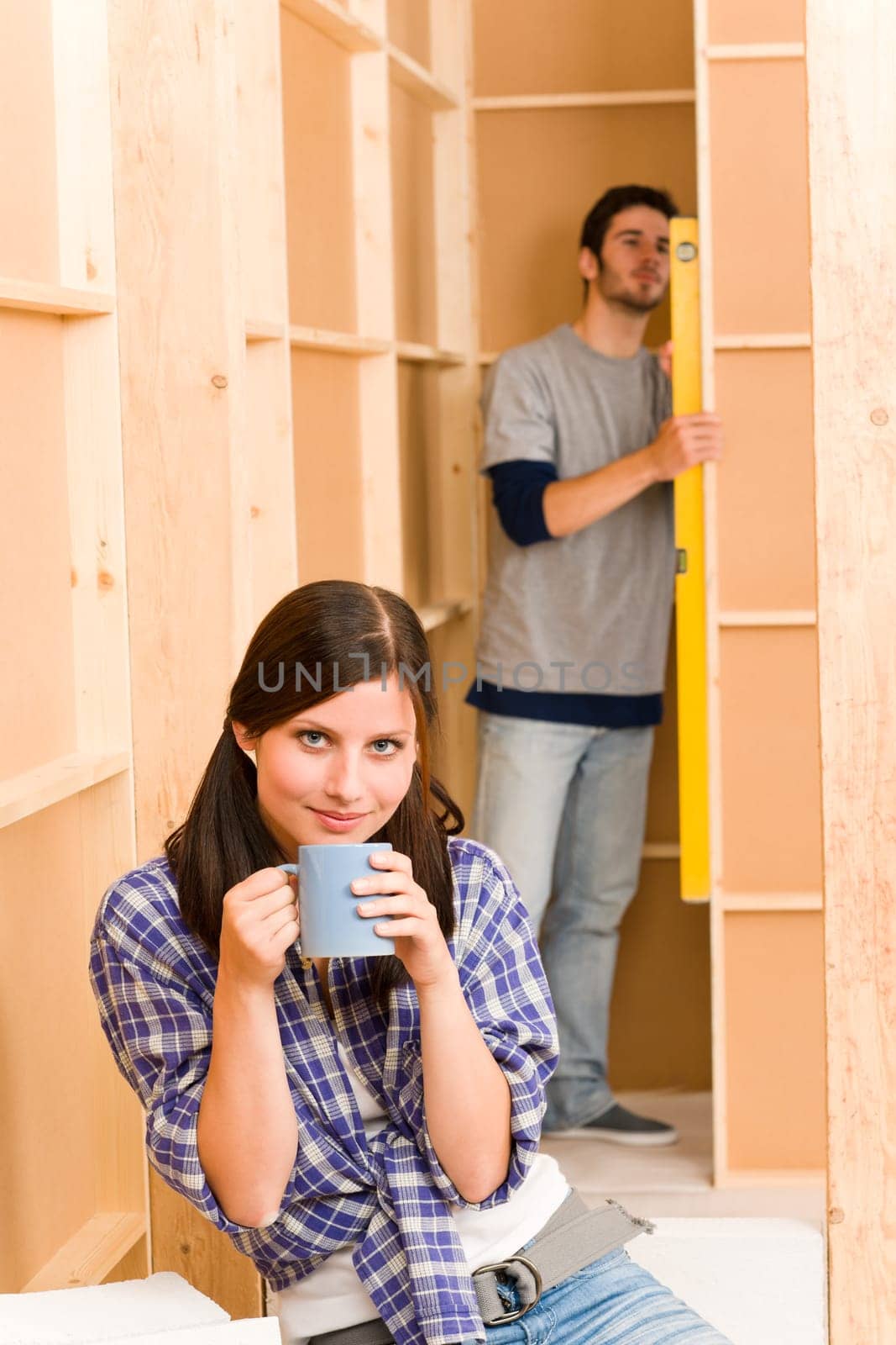Home improvement smiling young couple fixing wall with water level