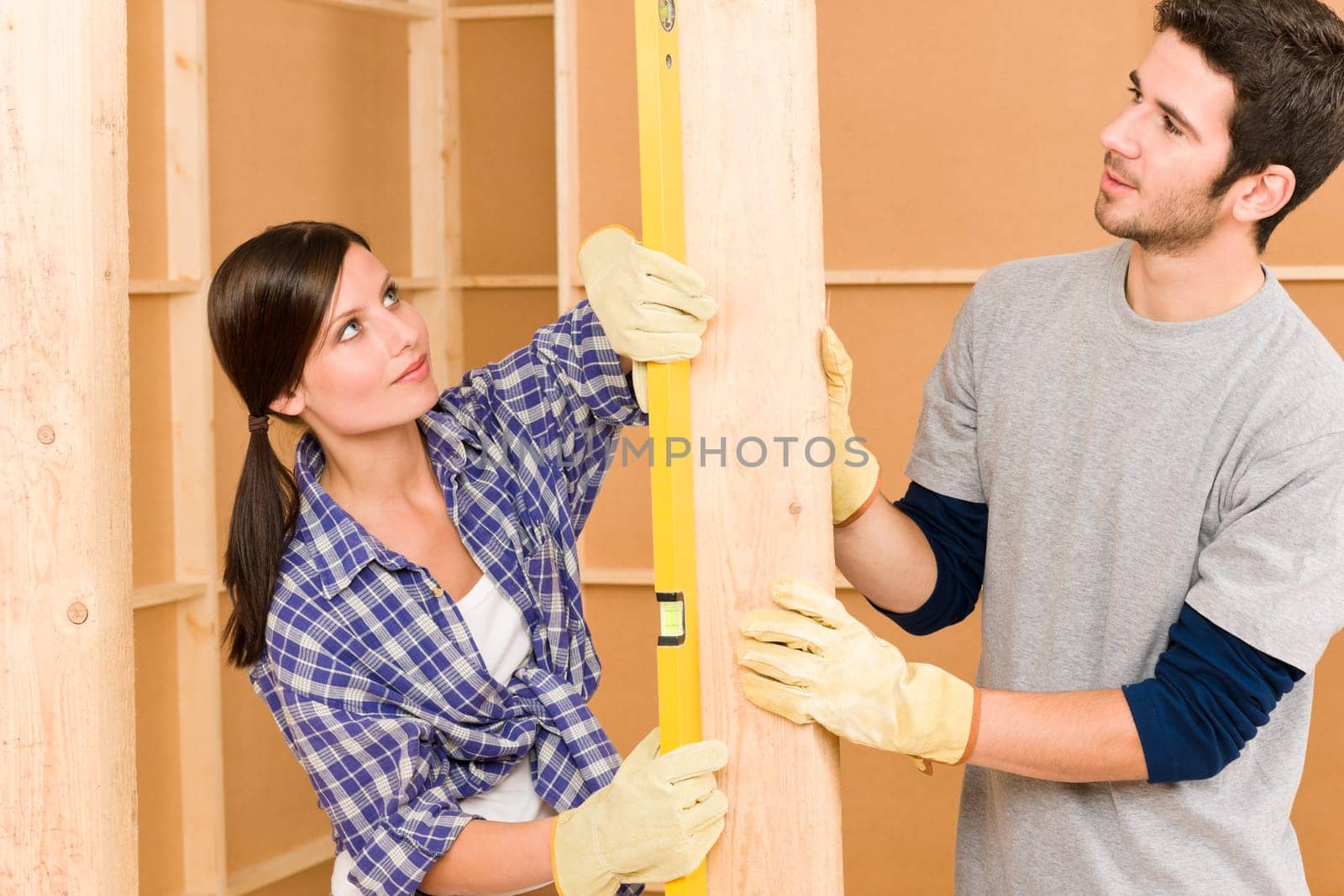 Home improvement smiling young couple fixing wall with spirit level