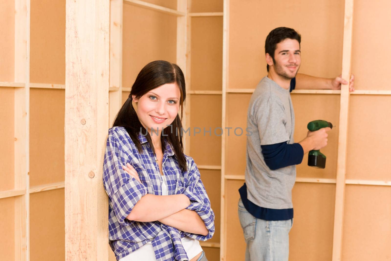 Home improvement smiling young couple fixing wall with hand drill