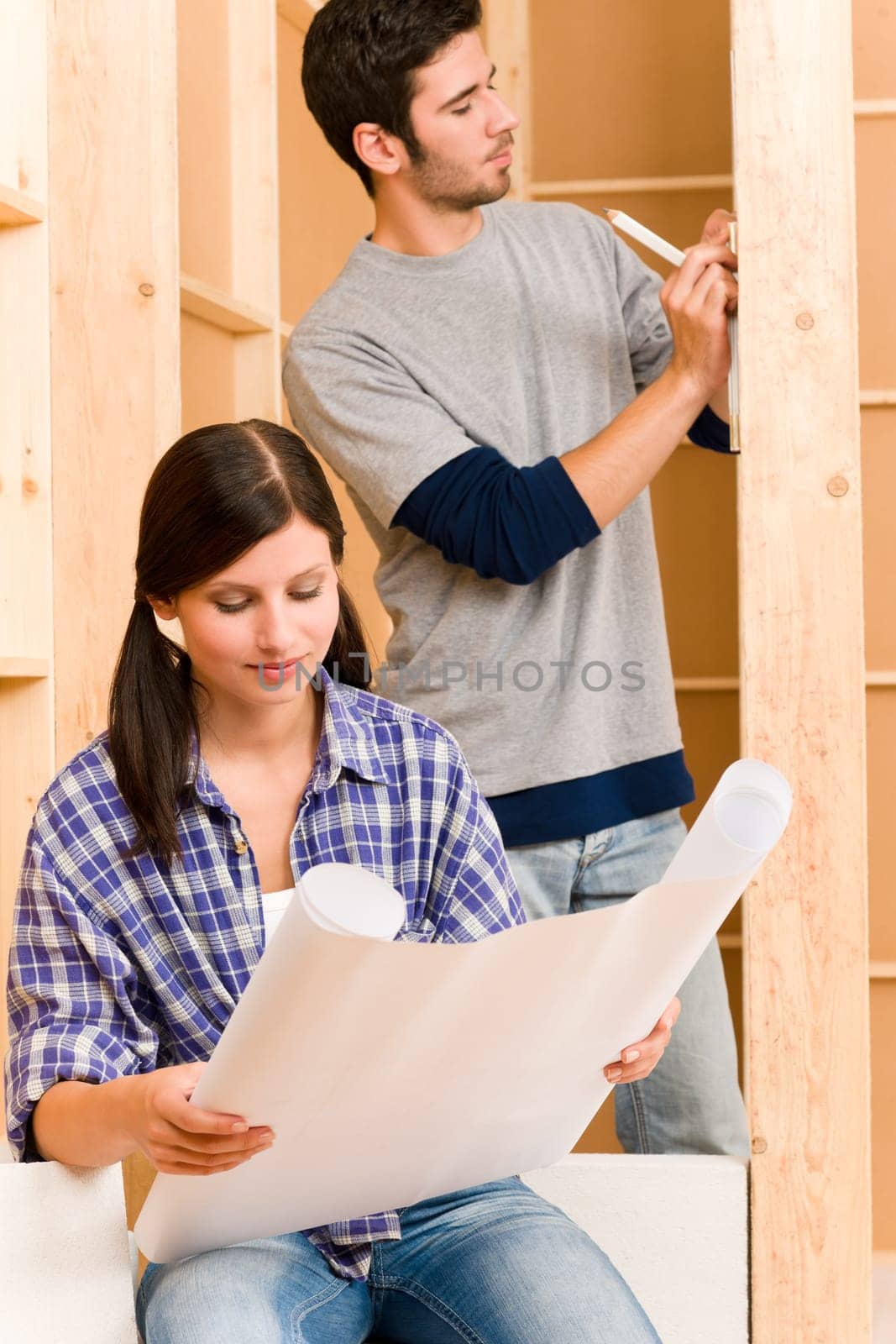 Home improvement happy young couple with architectural blueprints fixing house