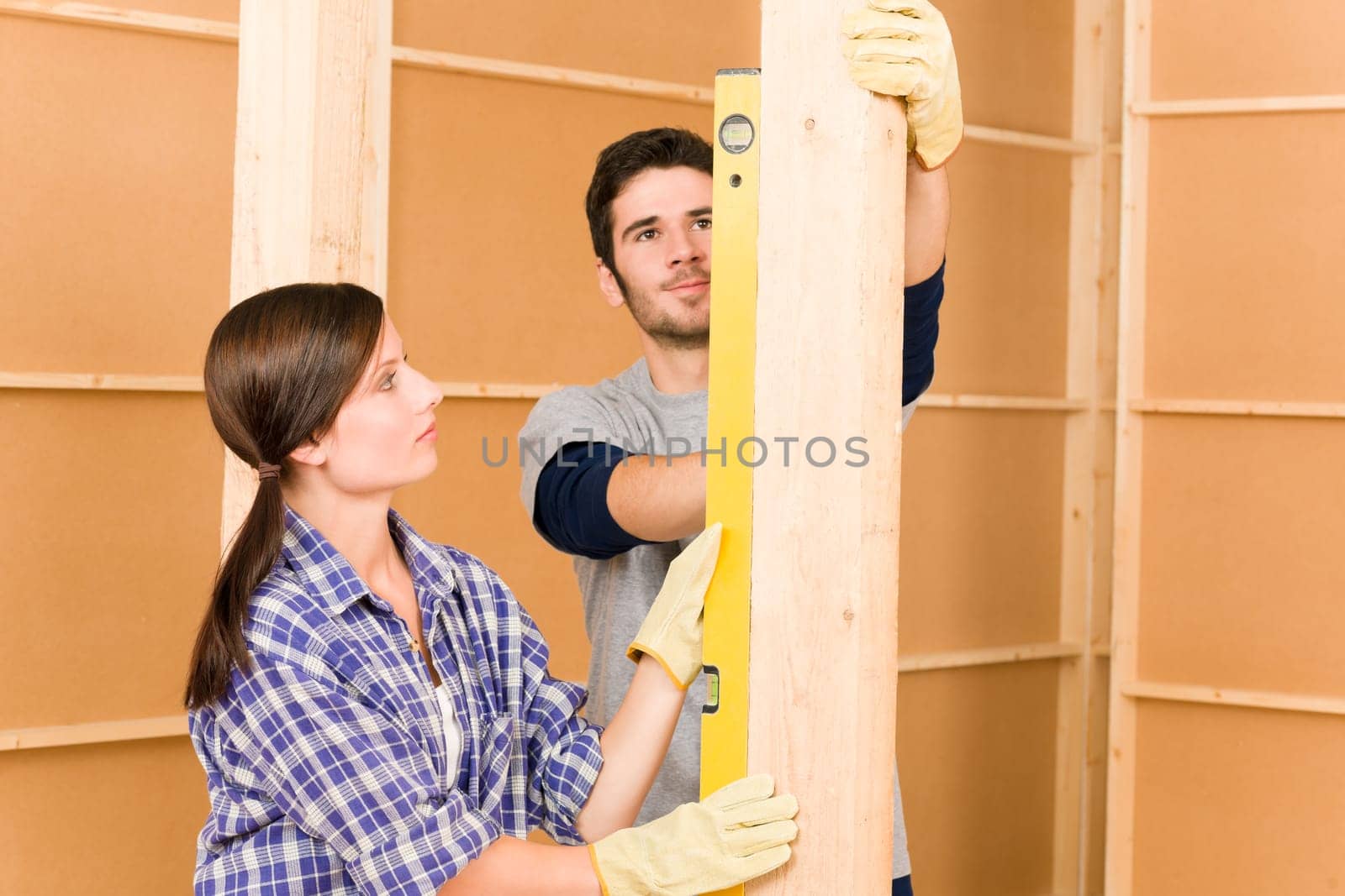 Home improvement smiling young couple fixing wall with spirit level