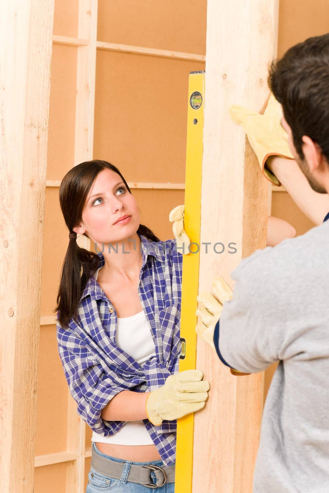 Home improvement smiling young couple fixing wall with spirit level