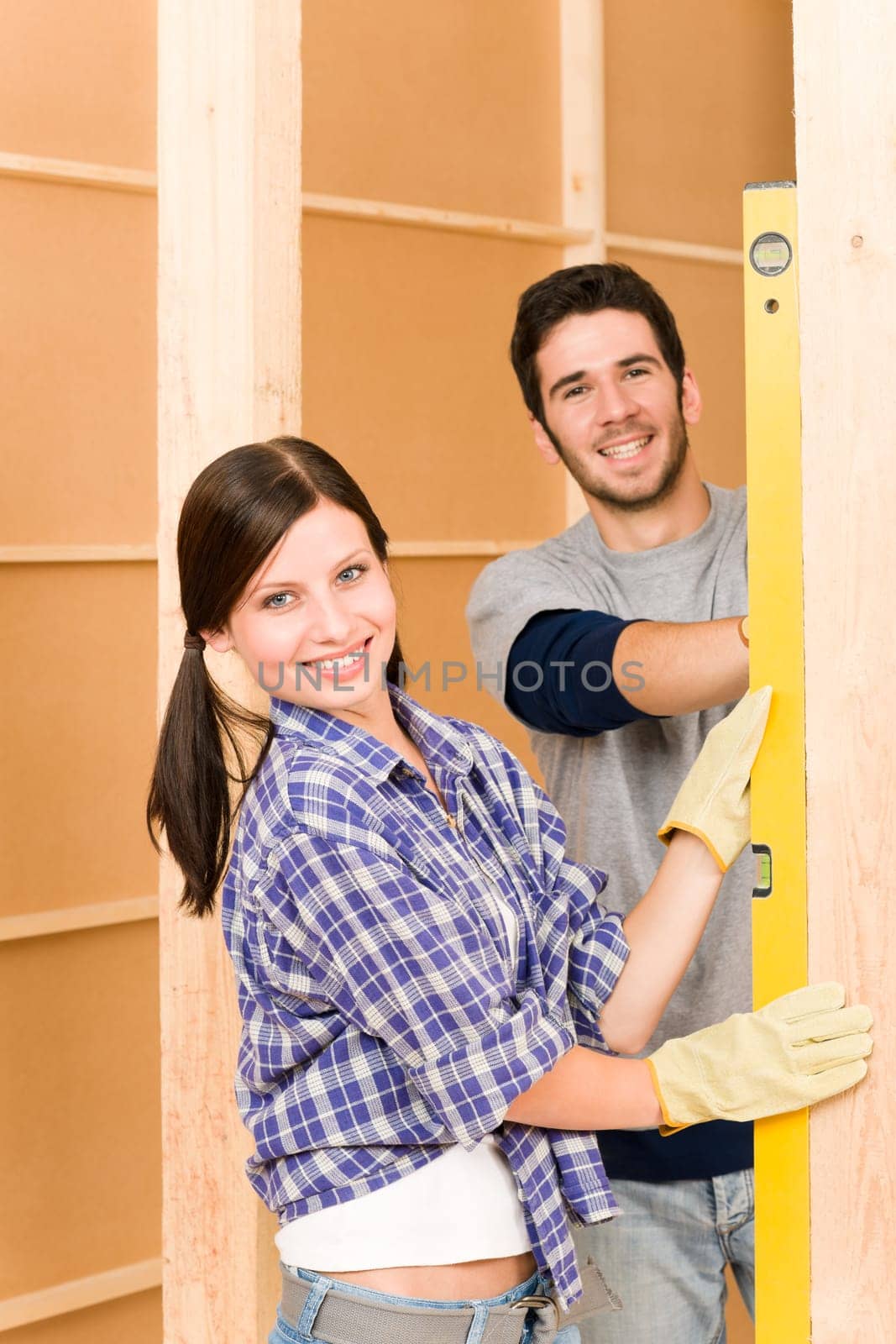 Home improvement smiling young couple fixing wall with spirit level