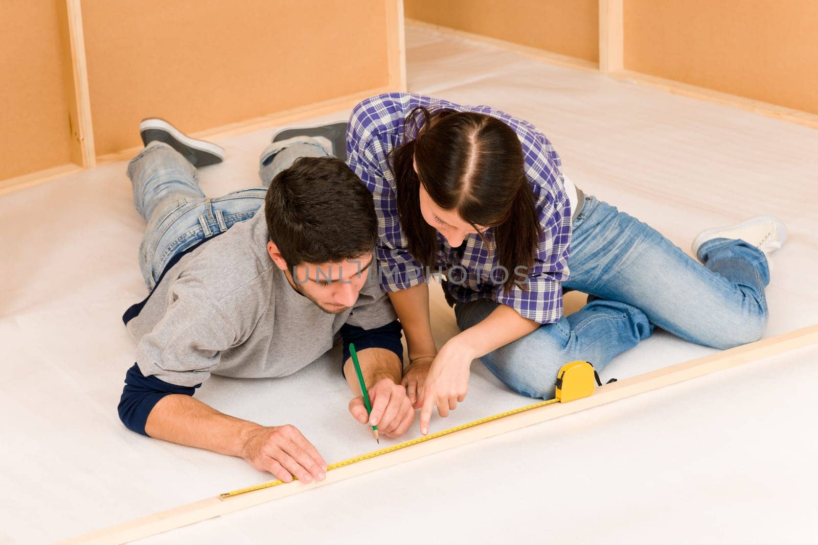 Home improvement young couple working on floor renovations measure rule