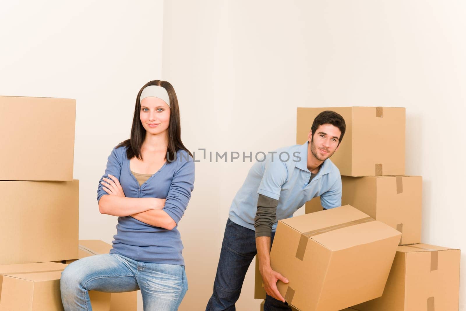 Happy young couple moving into new home carrying cardboard boxes