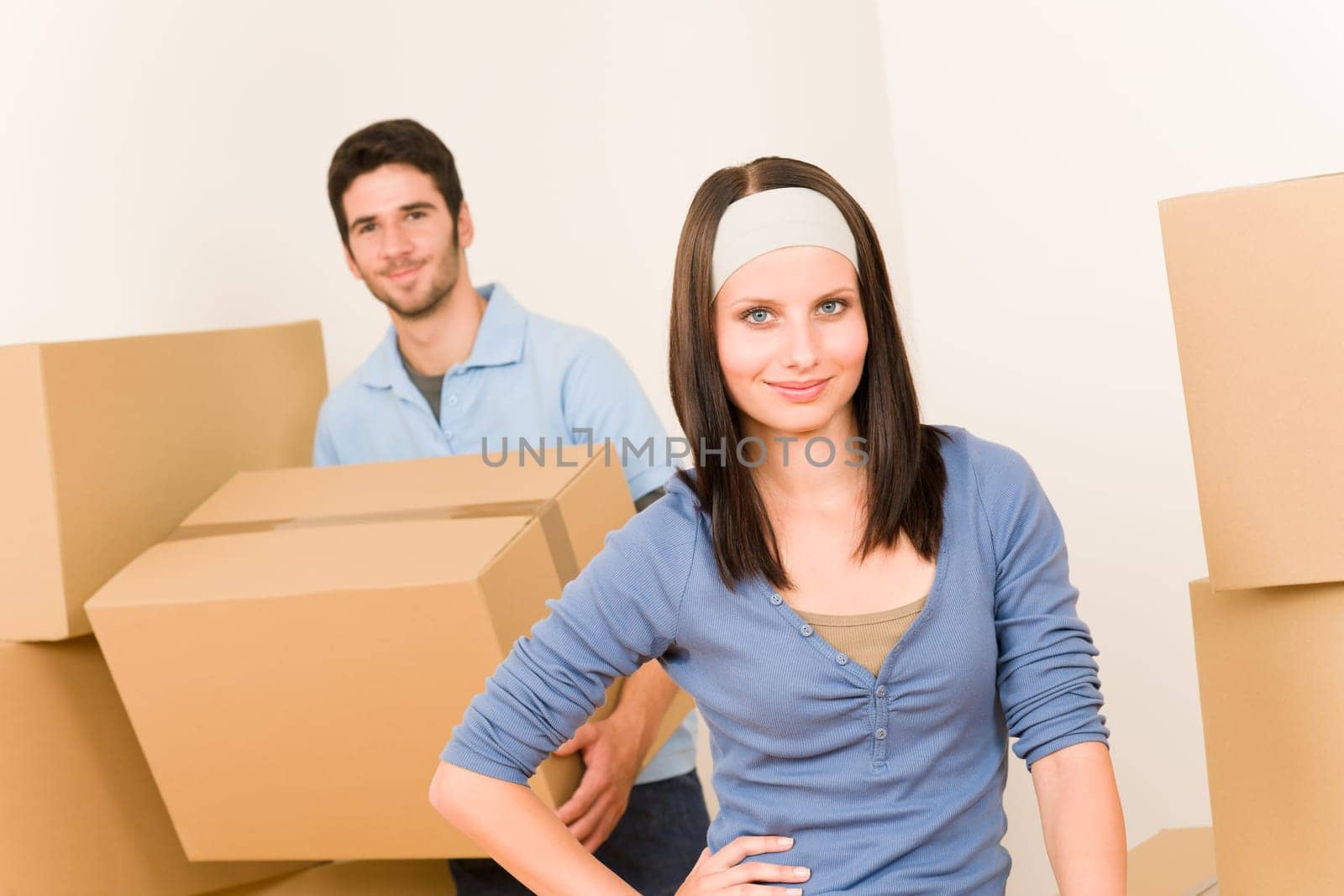 Happy young couple moving into new home carrying cardboard boxes
