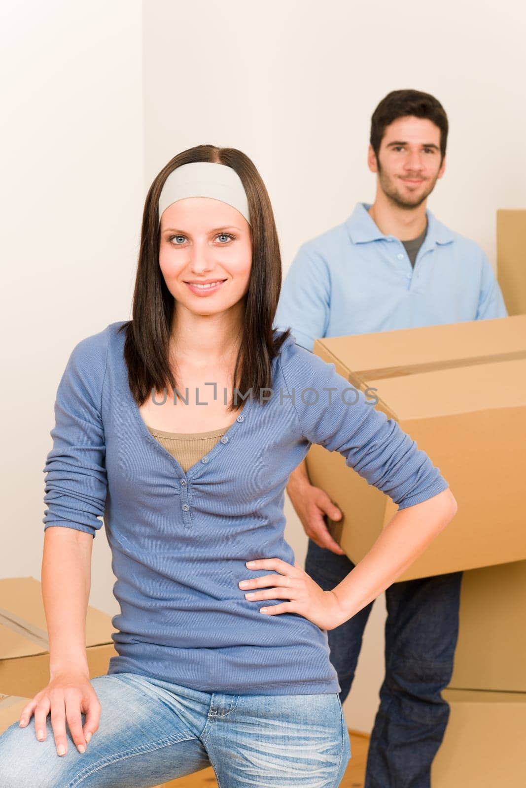 Happy young couple moving into new home carrying cardboard boxes